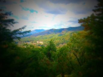 Alt tag: Scenic view of a mountainous landscape with lush green trees and rolling hills under a cloudy sky. Kitsuma mountain bike trail.