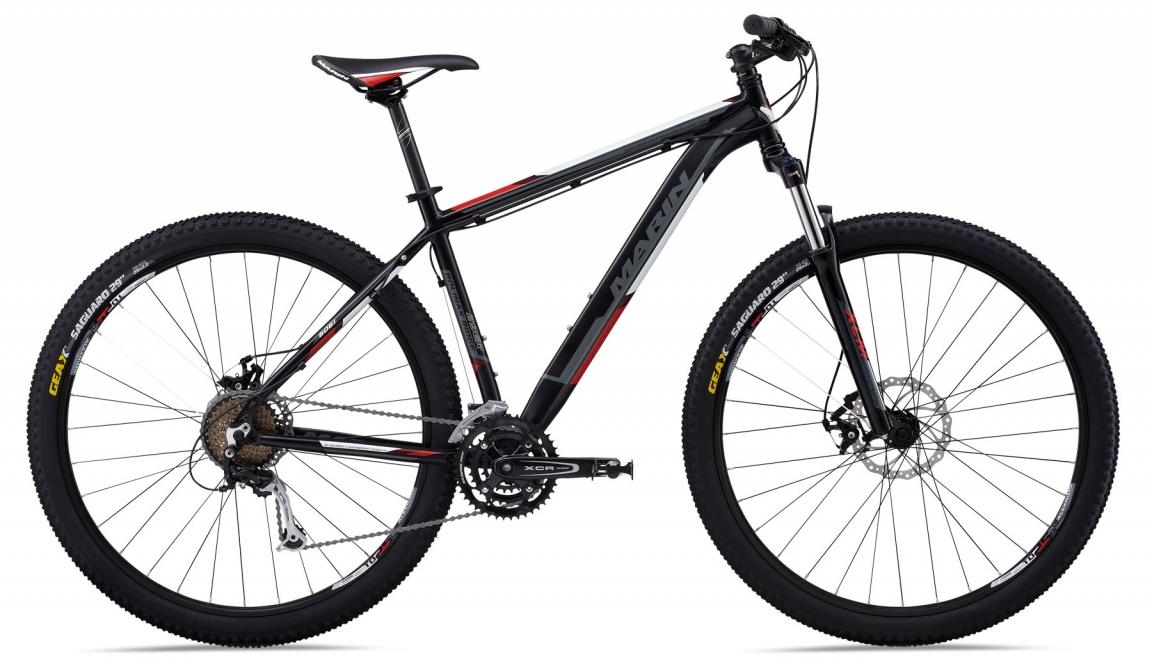 Marin Bobcat Trail: Alt text: A sleek black and red mountain bike with a lightweight frame, featuring thick, rugged tires suited for off-road trails, front suspension forks, and a simple gear system visible on the side.
