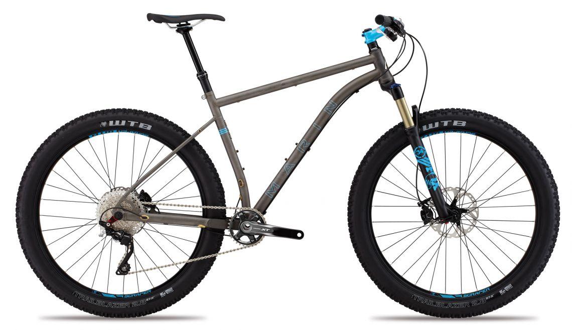 Marin Pine Mountain 2 27.5: Alt text: A modern mountain bike with a sleek, matte gray frame, featuring wide tires and a front suspension fork. The bike has blue accents, disc brakes, and a gear system, showcasing a sturdy build suitable for off-road trails.