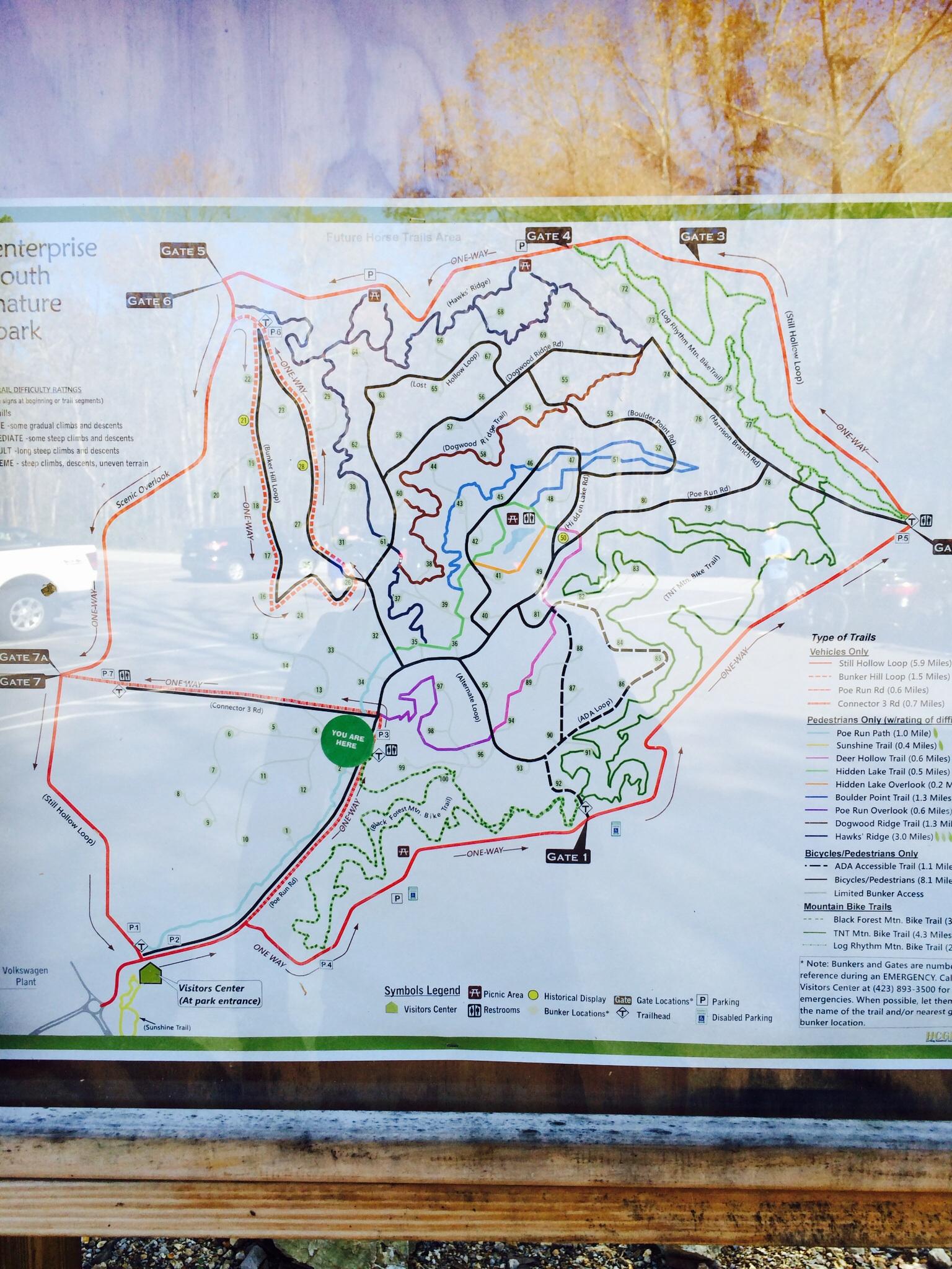 A detailed map of the Enterprise South Nature Park, featuring various trail routes for vehicles, pedestrians, bicycles, and mountain bikes. The map includes key locations such as gates, picnic areas, restrooms, and the visitors center, along with a legend explaining symbols and trail types. Key access points and landmarks are marked, with "You Are Here" indicating the current location within the park. Enterprise South mountain bike trail.