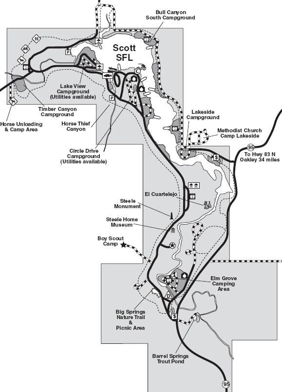Map of Scott State Fishing Lake, featuring campground locations, hiking trails, and landmarks such as the Steele Home Museum and El Cuarteljo. Roads and pathways are illustrated, indicating routes to various sites and distances to nearby highways. Lake Scott State Park mountain bike trail.