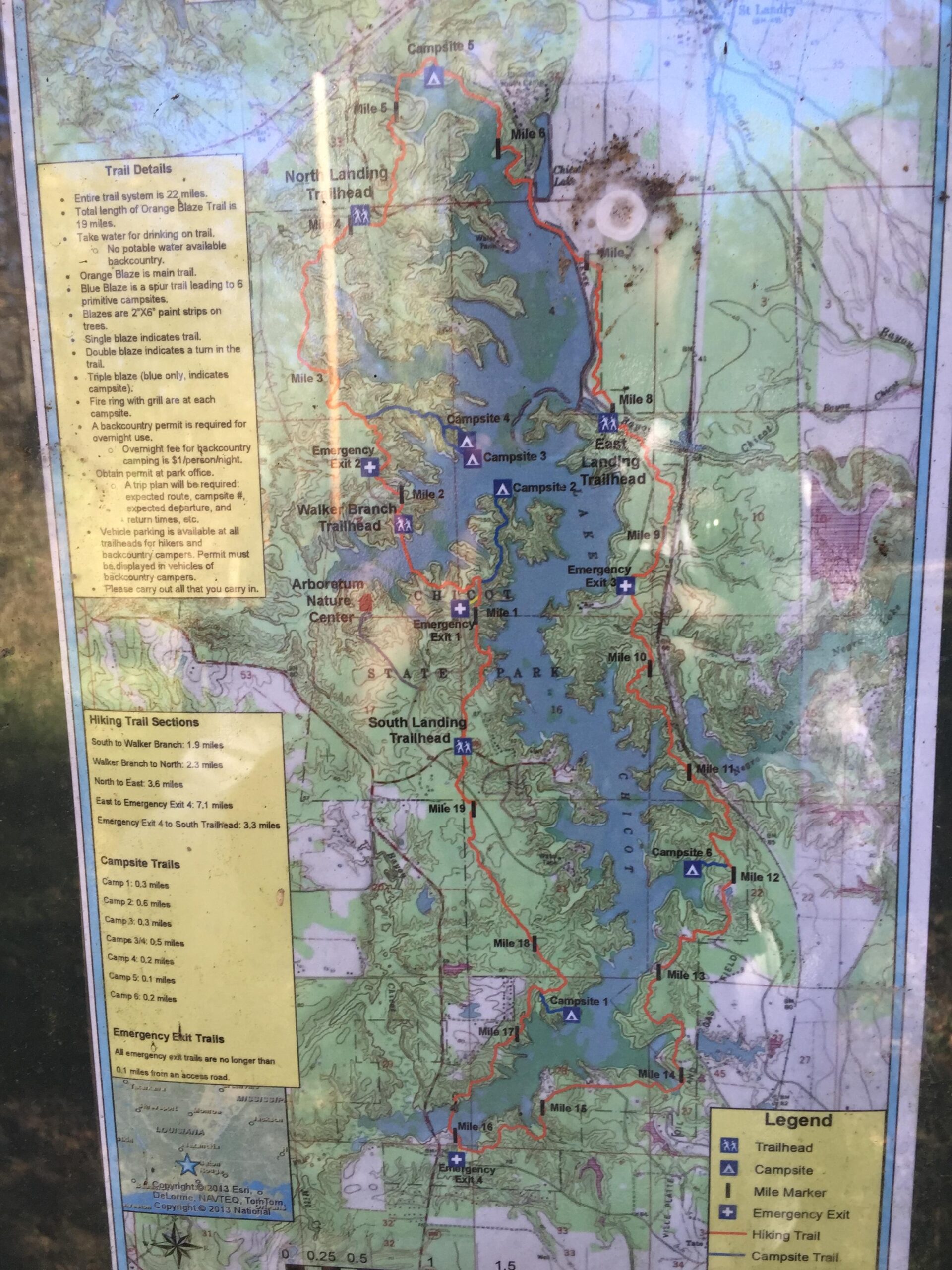 Map of a hiking trail system spanning 22 miles, featuring detailed information on trail sections, campsites, and emergency exits. The map highlights the Orange Blaze Trail, various hiking and campsite trails, and includes a legend for navigation. Notable points are marked, including trailheads and emergency exits, alongside mileage for different routes and camping areas. Chicot State Park mountain bike trail.