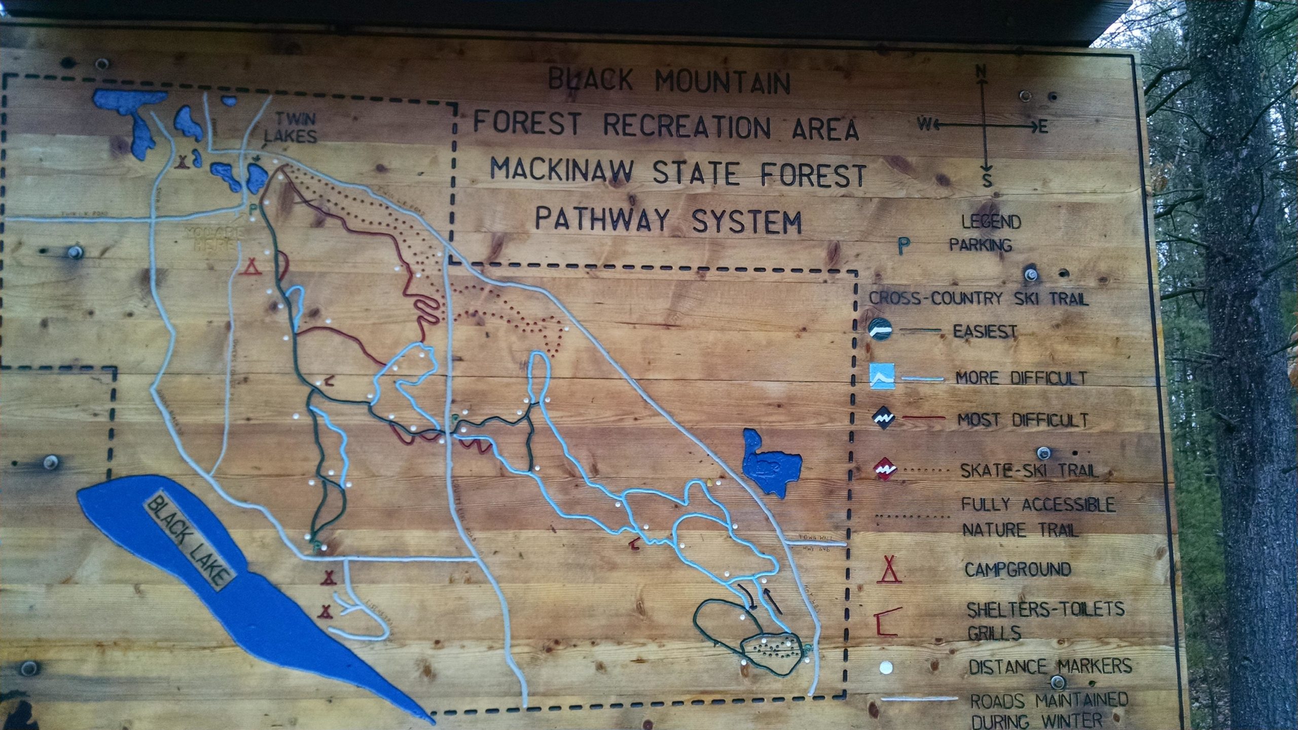 Map of Black Mountain Forest Recreation Area, showing the Mackinaw State Forest pathway system. Includes labeled trails for cross-country skiing of varying difficulty, fully accessible nature trails, and amenities like campgrounds and distance markers. The map features locations for Twin Lakes and Black Lake, alongside a legend for trail types and parking details. Black mountain recreation area mountain bike trail.