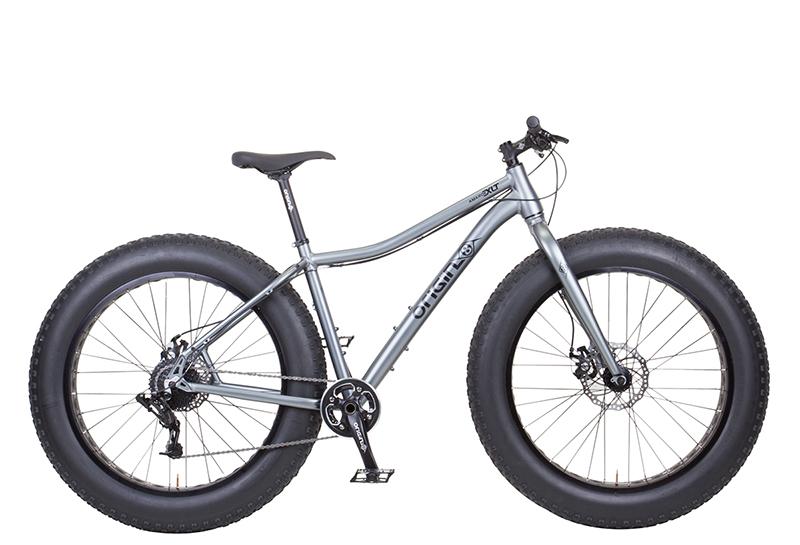 Origin-8 Amarok: A silver fat bike with wide tires and a modern frame design, showcasing front suspension and disc brakes. The bike is positioned on a white background.