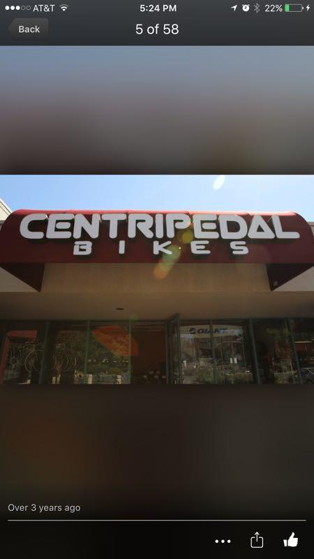 Sign displaying the name "CENTRIPEDAL BIKES" above a bike shop entrance, with bicycles visible through the windows.