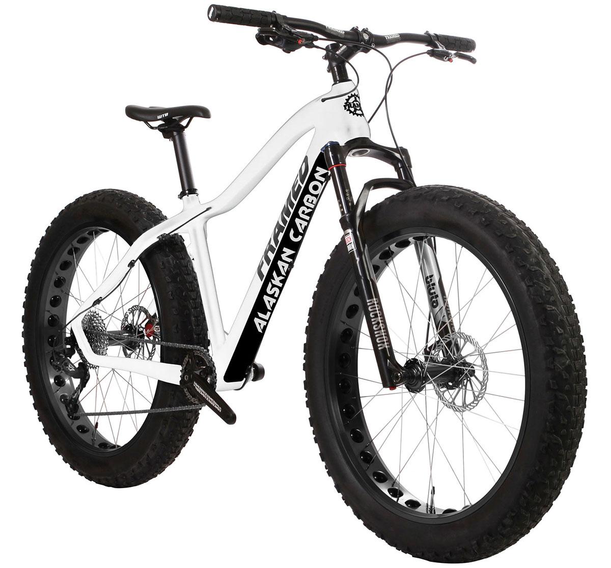 Framed Alaskan Carbon: Alt tag: A white fat bike with large, knobby tires and a carbon frame, featuring the text "Alaskan Carbon" on the frame, showcasing a modern design suitable for off-road and snowy conditions.