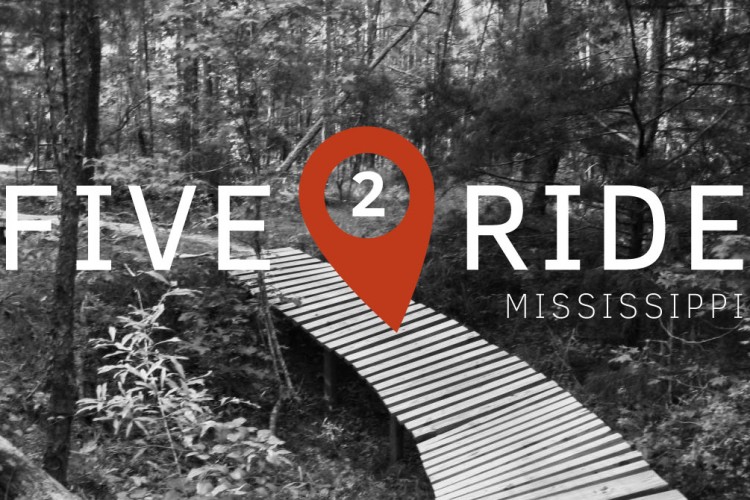 A wooden boardwalk winding through a wooded area, overlaid with the text "FIVE 2 RIDE" and a location marker icon in orange, along with the word "MISSISSIPPI." The image is predominantly in black and white, highlighting the natural surroundings.