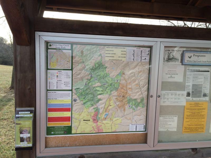 Map display board at White Clay Creek State Park, featuring a detailed topographic map of the area with trail information, park amenities, and additional program details. White Clay Creek mountain bike trail.