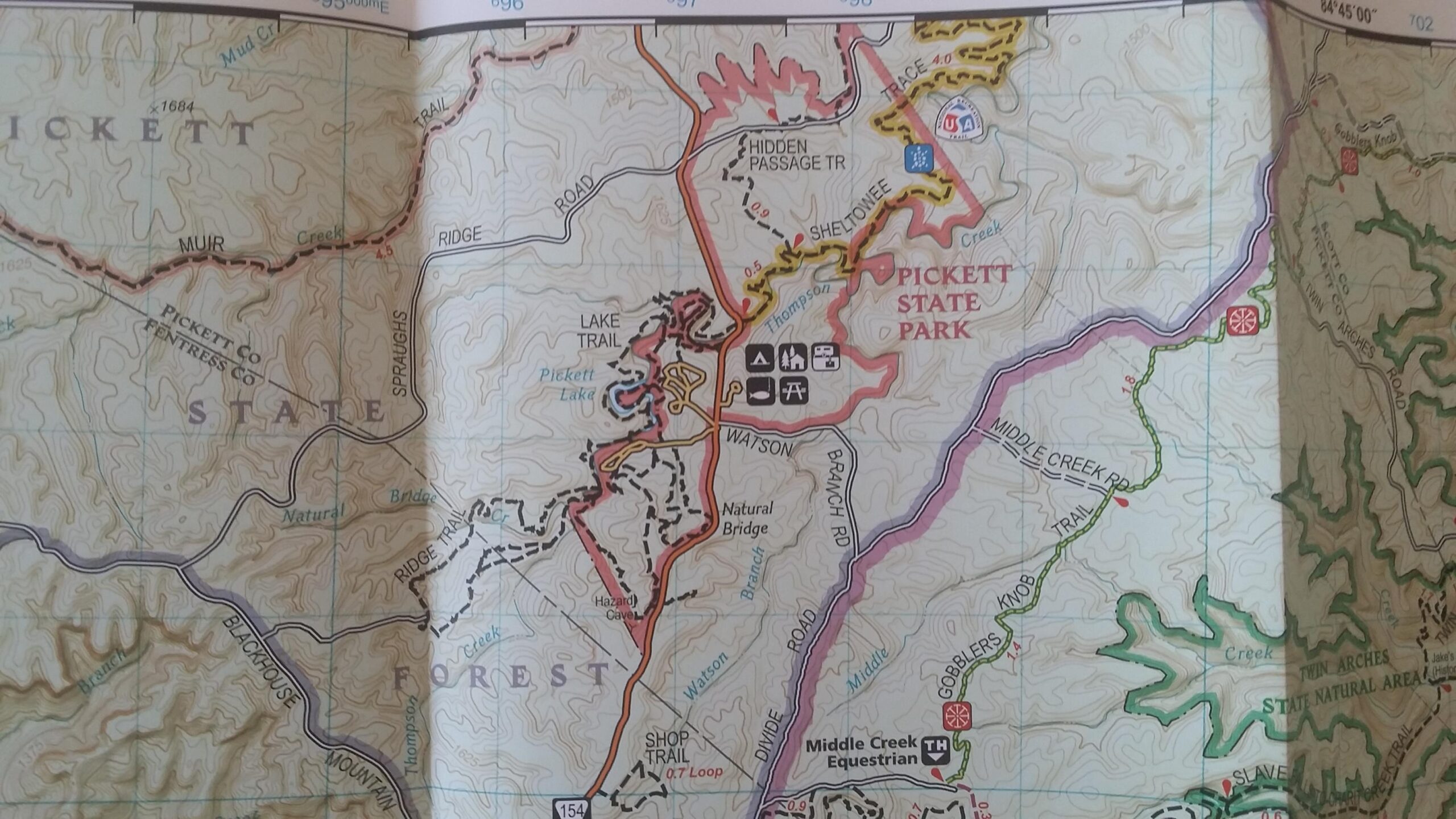 Map of Pickett State Park, displaying various trails, roads, and landmarks including Pickett Lake and Natural Bridge. The map includes contour lines and symbols for parking and recreation areas. Big South Fork mountain bike trail.