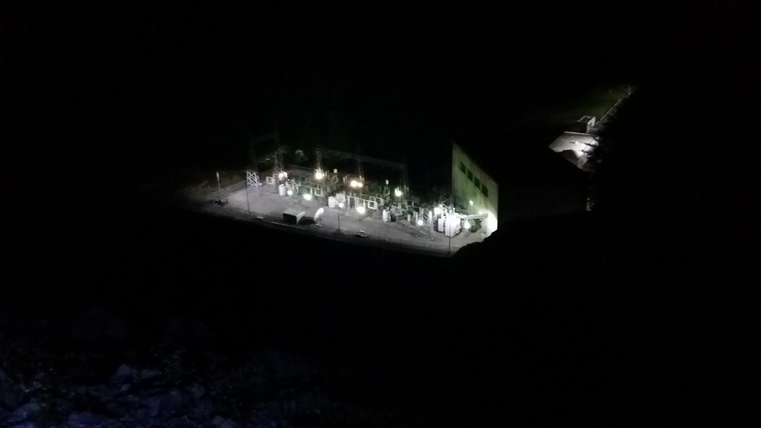 An illuminated electrical substation at night, showcasing various equipment and structures against a dark background. Sheltowee Trace - Laurel Lake Trail mountain bike trail.