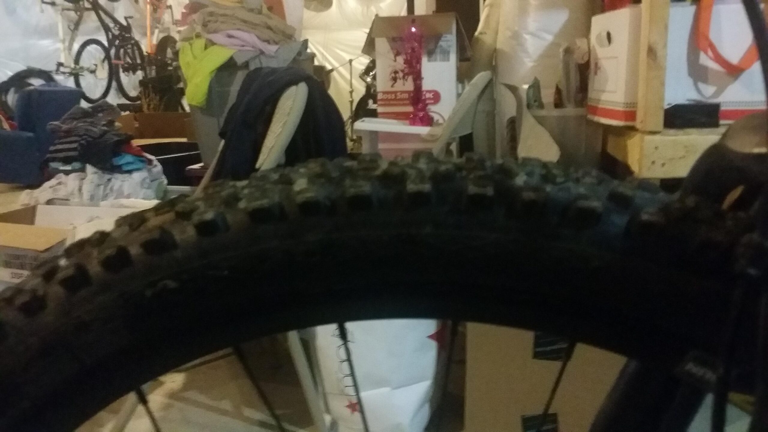 Schwalbe Hans Dampf: A close-up image of a mountain bike tire with visible tread patterns, set against a cluttered garage background filled with bicycles, boxes, and laundry.