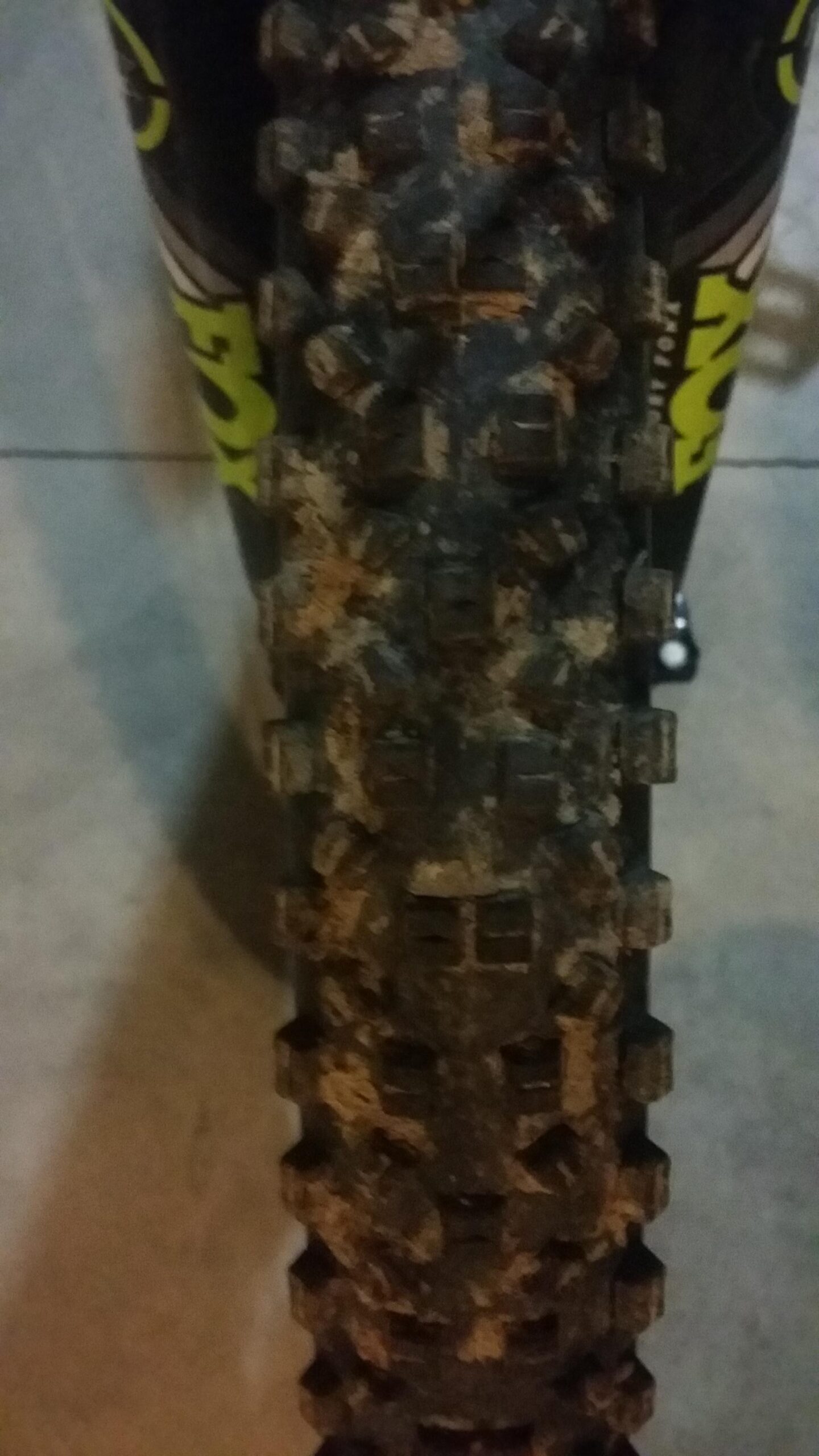 Schwalbe Hans Dampf: Close-up image of a muddy bicycle tire showing its textured tread pattern against a blurred background. The tire has visible dirt and grime, indicating it has been used off-road.