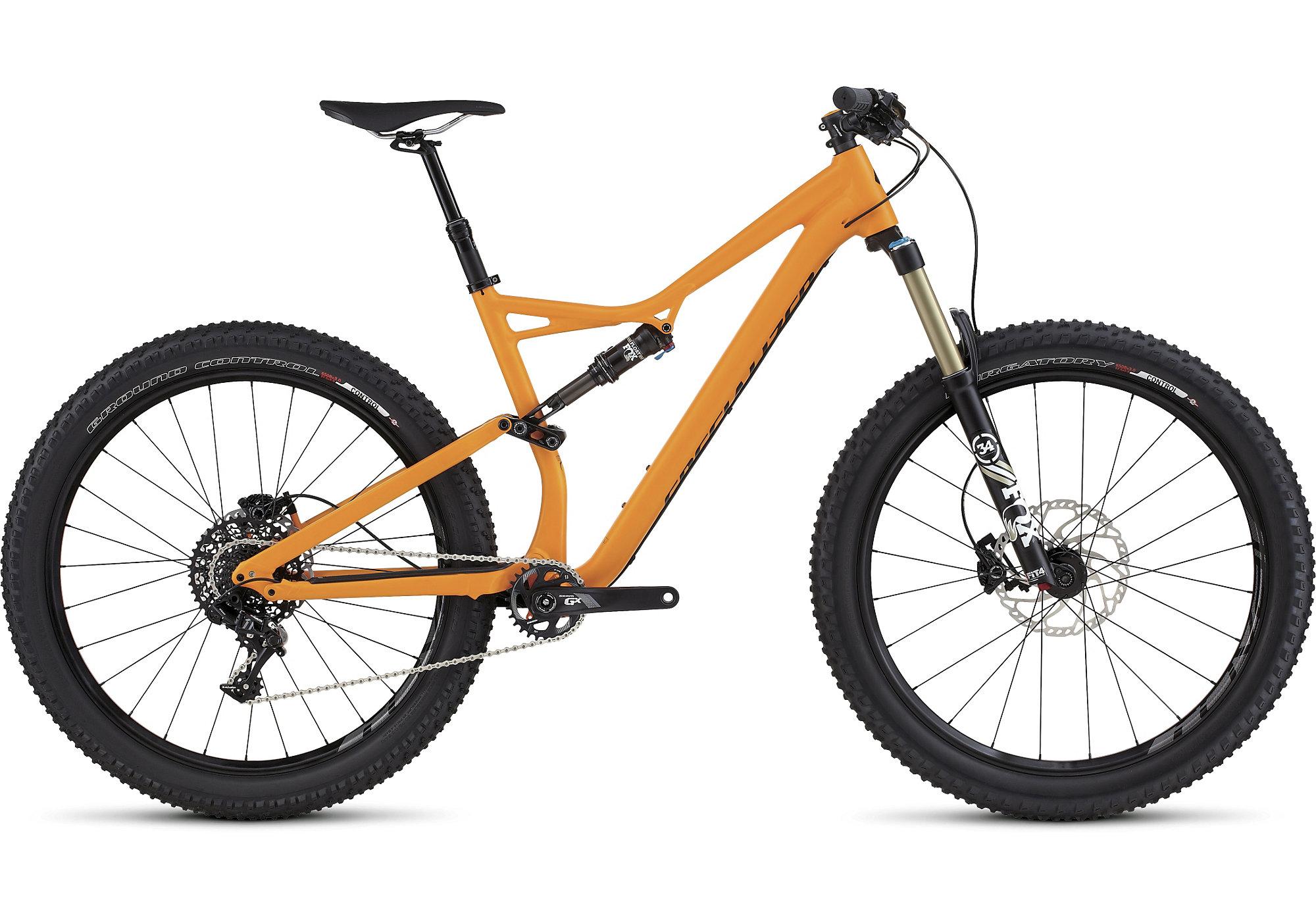 Specialized Stumpjumper FSR 6Fattie: Alt text: An orange mountain bike with a sleek frame design, wide tires, and front suspension fork. The bike is positioned on a white background, showcasing its components, including a rear derailleur, disc brakes, and a dropper seat post.