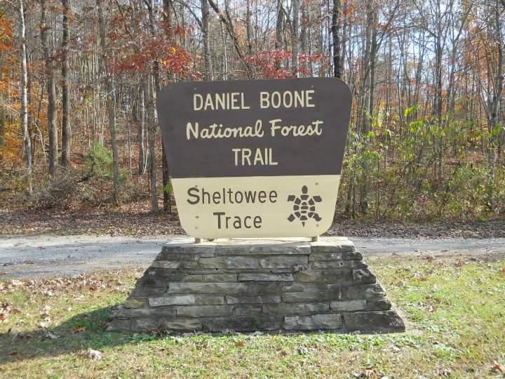 Sign marking the beginning of the Sheltowee Trace trail in the Daniel Boone National Forest, surrounded by autumn foliage and trees. Sheltowee Trace - Laurel Lake Trail mountain bike trail.