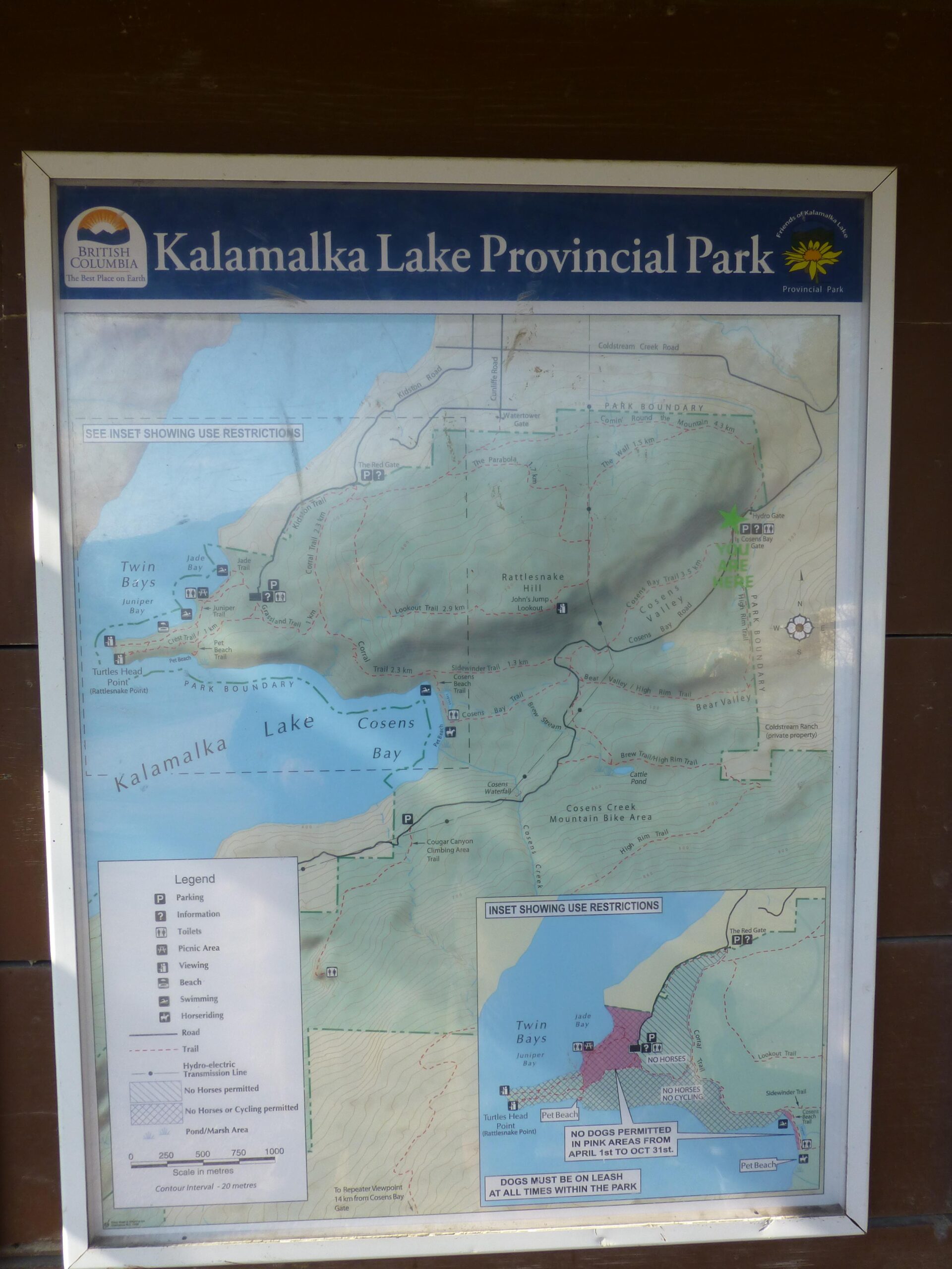 Map of Kalamalka Lake Provincial Park, displaying trails, parking areas, and recreational zones, including restrictions for dogs and specific activities. The map features sections of Kalamalka Lake, Twin Bays, Cosens Bay, and surrounding points of interest, with a legend indicating facilities and terrain details. An inset highlights use restrictions in pink areas. Kalamalka Lake Provincial Park mountain bike trail.