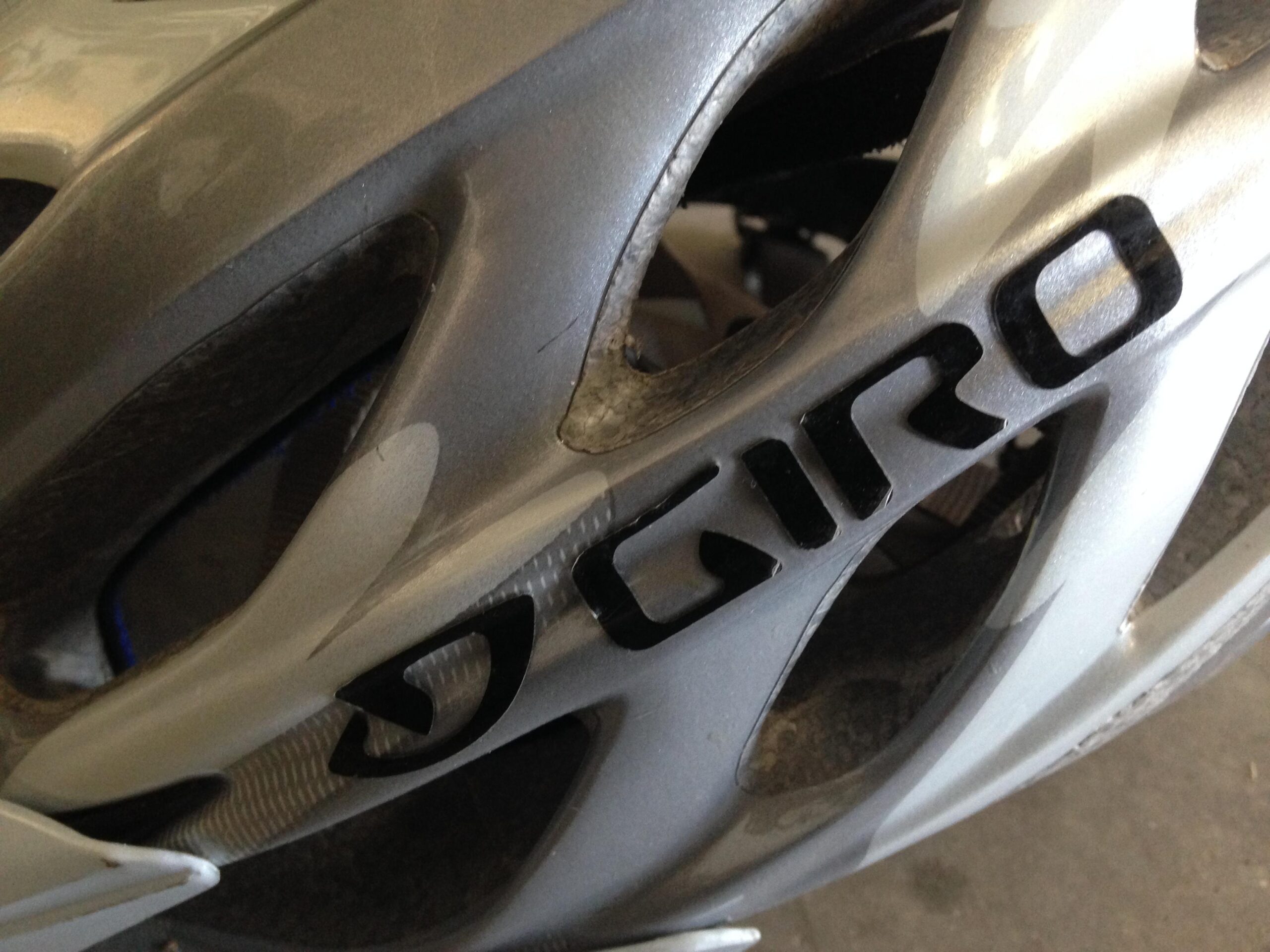 Close-up view of a silver cycling helmet featuring the brand name "Giro" prominently displayed on the side, showcasing the helmet's ventilation openings and design details.