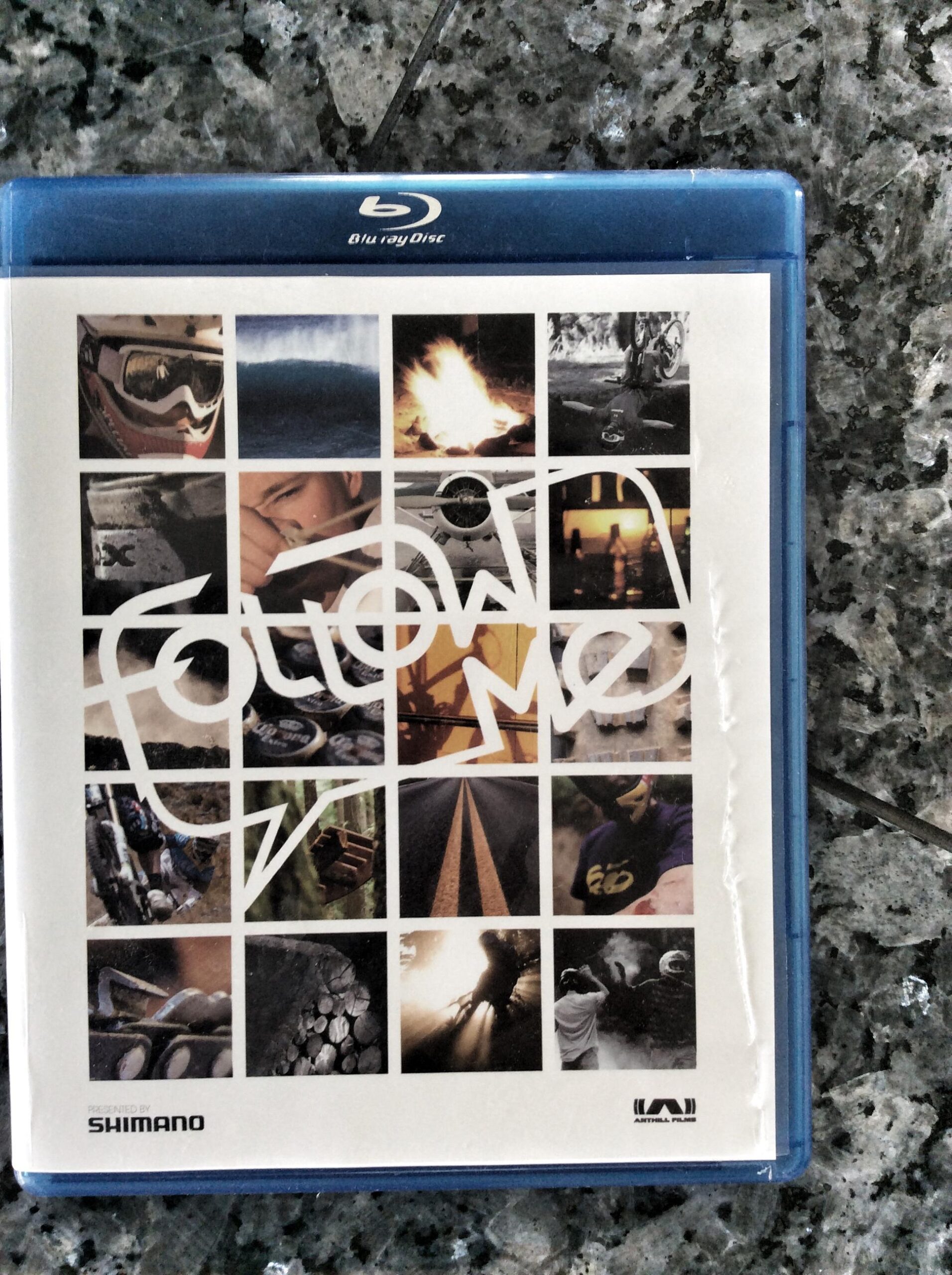 Blu-ray cover of the film "Follow Me" featuring a collage of images including action sports, nature scenes, and vibrant colors, with the title "Follow Me" prominently displayed in bold white lettering. The cover is presented against a textured surface, with the Blu-ray case visible at the top.