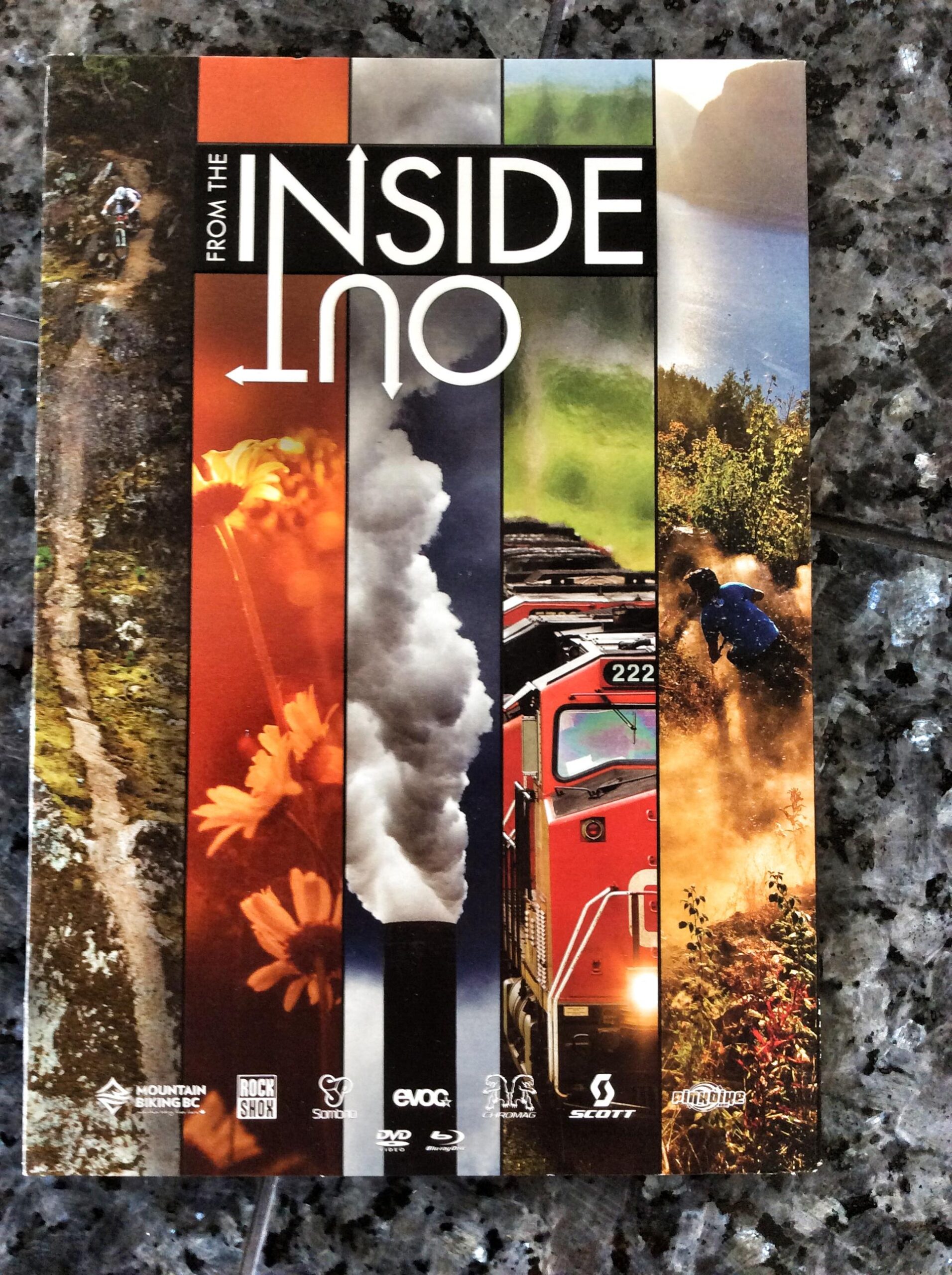 A vertically oriented image featuring a collage of colorful photographs on the left side, showcasing various outdoor scenes, including biking and nature. The central part of the image has the title "FROM THE INSIDE OUT" in bold white letters on a black background. The whole composition includes logos from sponsors at the bottom. The background is a textured black granite surface.