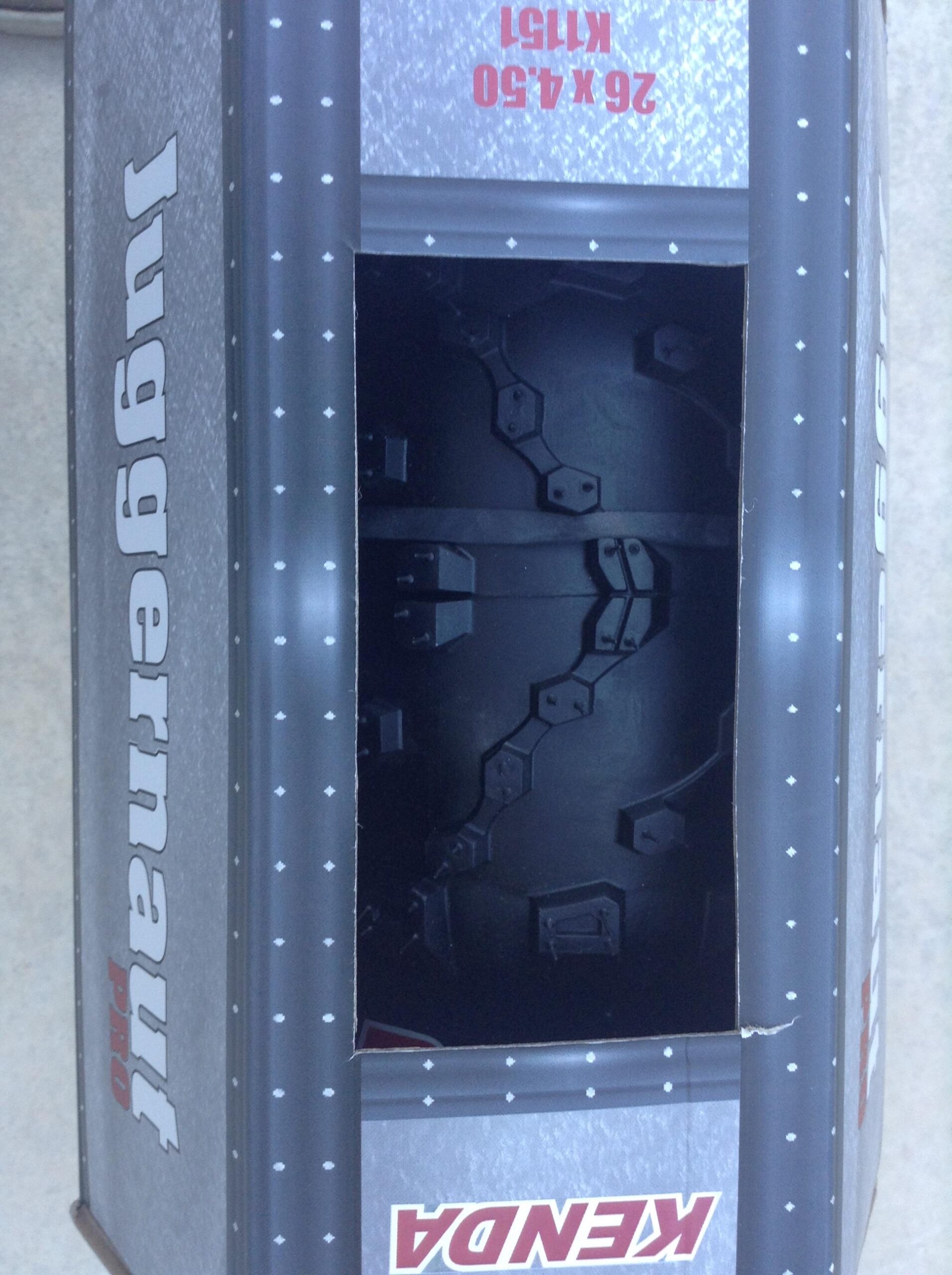 Kenda Juggernaut: A partially open box labeled "Juggernaut Pro" with visible interior detailing, featuring a dark, textured surface and geometric shapes. The dimensions "26X4.30" are printed on the side, and the branding is presented prominently.