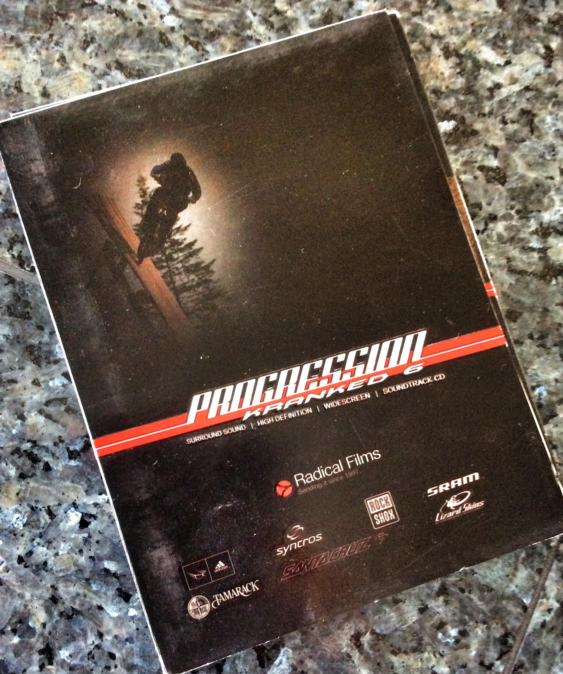 A DVD cover for "Progression: Kranked 6," featuring a silhouette of a cyclist performing a trick on a wooden beam against a dark background. The cover includes the words "Surround Sound," "High Definition," "Widescreen," and features logos of various sponsors, including Radical Films, Syncros, Rock Shox, SRAM, and Santa Cruz. The overall aesthetic conveys an adventurous and dynamic vibe related to mountain biking.