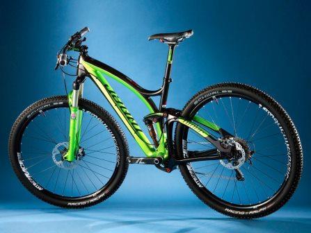 Niner Jet 9 RDO: A modern mountain bike with a lightweight frame featuring a vibrant green and black color scheme, showcasing thick tires and a front suspension, positioned against a solid blue background.
