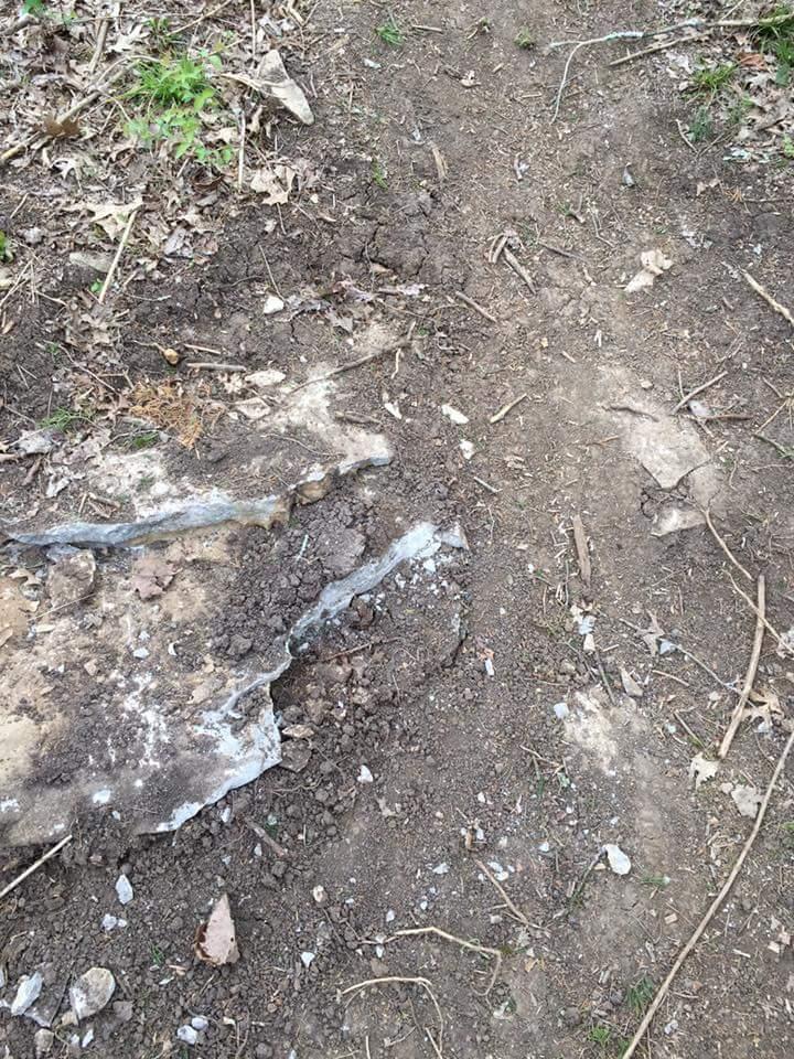 A dirt trail showing exposed rock and soil, surrounded by leaves and small plants. The ground is uneven with patches of dirt and stones visible. Knucklehead mountain bike trail.