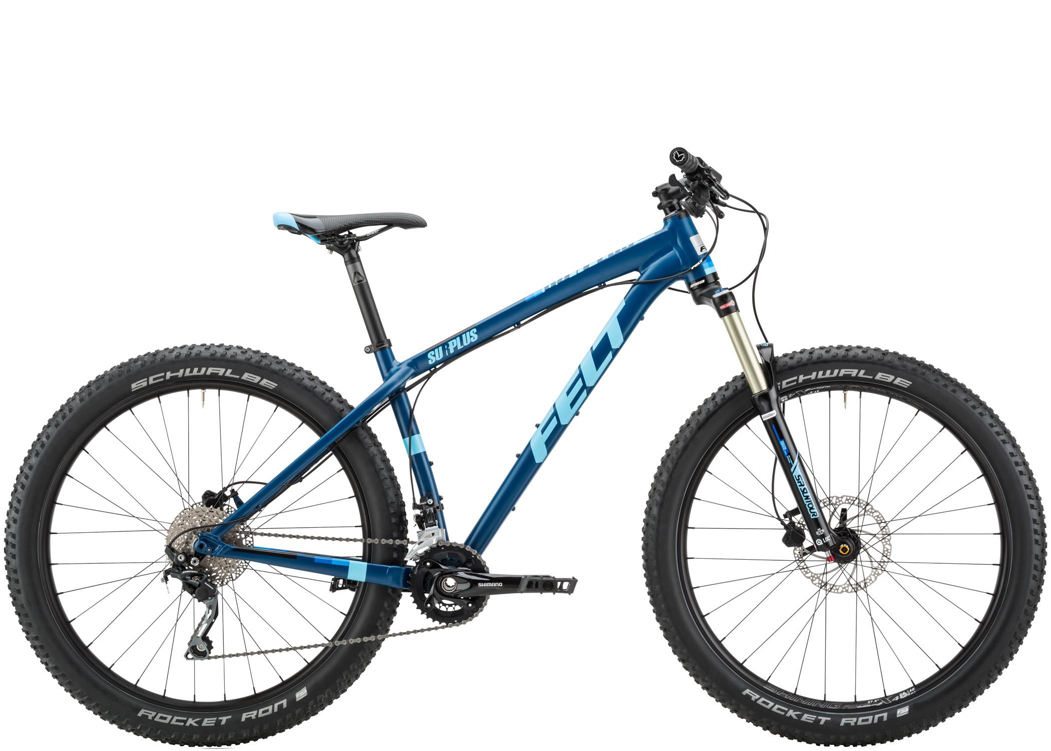 Felt Surplus: A blue mountain bike with a sleek frame design, featuring wide tires and a front suspension fork, positioned against a white background. The bike is branded with "Felt" and "Surplus." The components include Shimano drivetrain parts and Schwalbe Rocket Ron tires, indicating its suitability for rugged terrain.