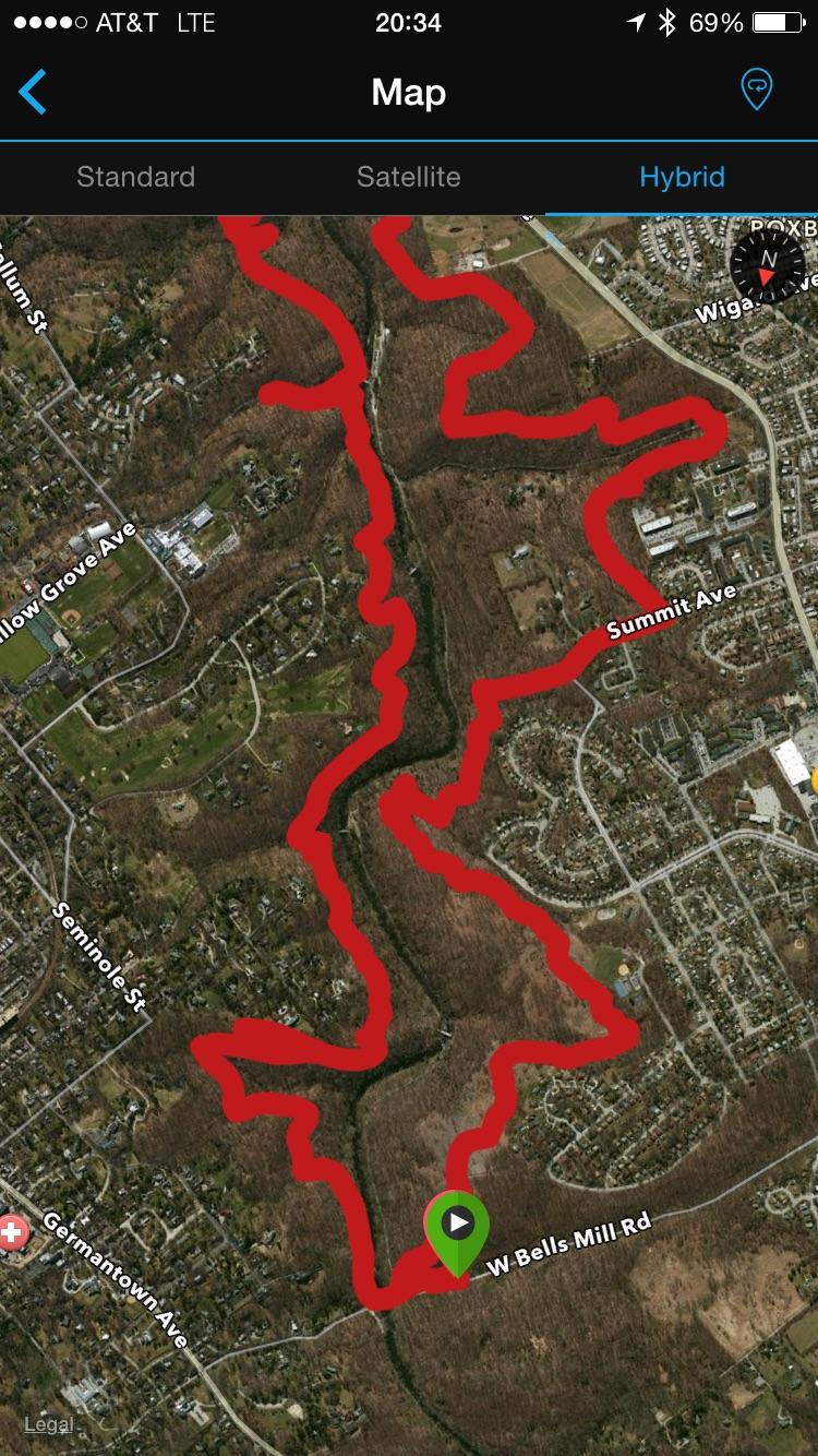 Map displaying a hybrid view of a wooded area with a red outlined path and various road names, including W Bells Mill Rd, Summit Ave, and Seminole St. The map features a green location icon indicating a specific point of interest within the outlined area. Wissahickon Valley Park mountain bike trail.