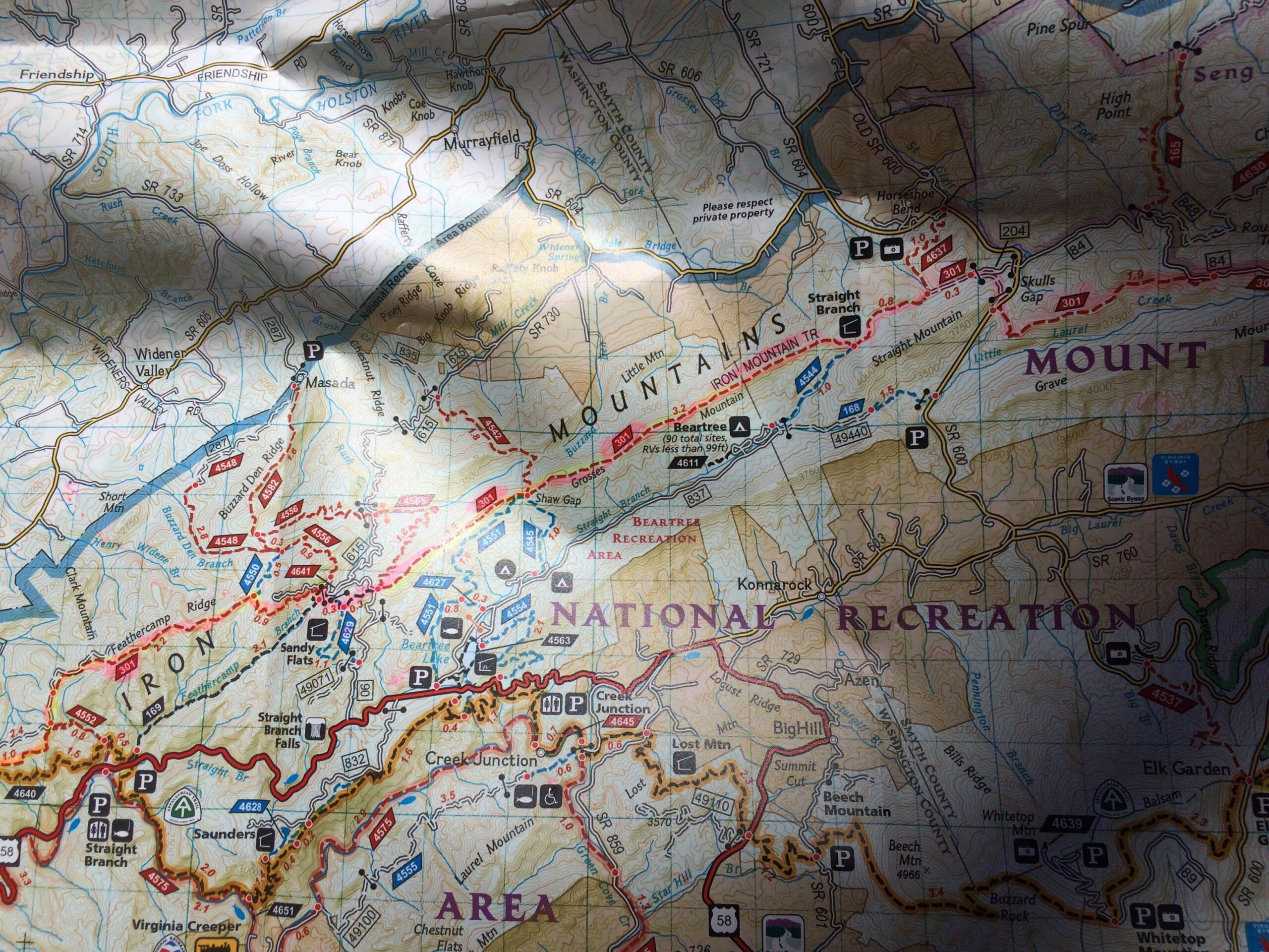 Detailed topographic map featuring the Iron Mountain area and surrounding regions, showing trails, parking locations, and notable features within a national recreation area. The map includes contour lines, landmarks, and routes for outdoor activities. Shadows partially obscure some details. Iron Mountain mountain bike trail.