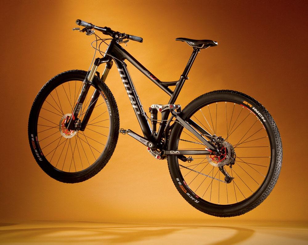 Niner Jet 9: A sleek black mountain bike displayed in mid-air against a warm orange background, showcasing its frame, wheels, and suspension system.