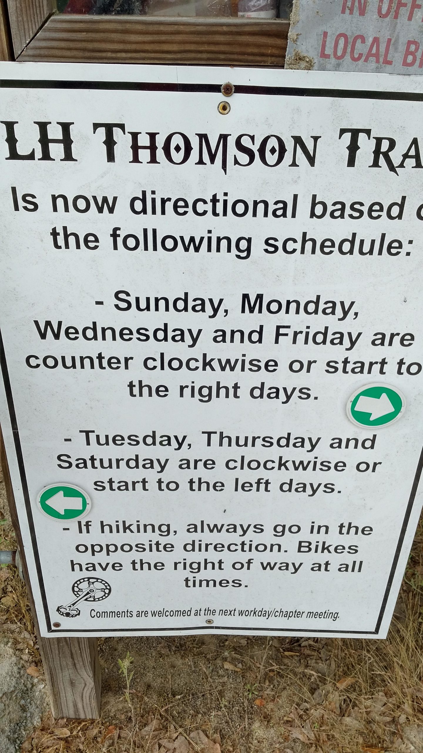 Sign detailing the directional schedule for LH Thomson Trail, stating that on Sundays, Mondays, Wednesdays, and Fridays, the direction is counterclockwise; on Tuesdays, Thursdays, and Saturdays, the direction is clockwise. It advises hikers to go in the opposite direction of bikers, who have the right of way. L.H. Thomson Trails mountain bike trail.