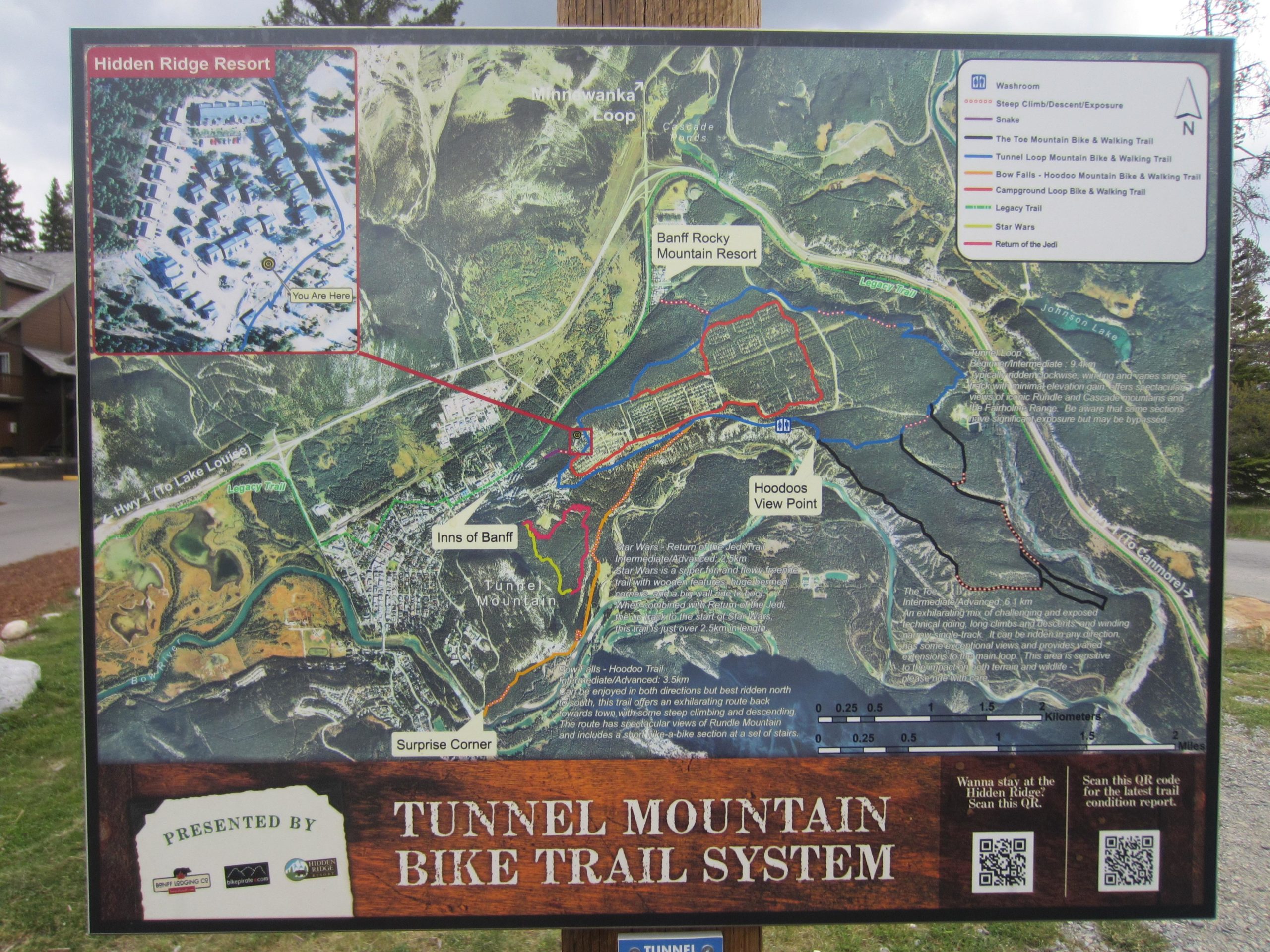 Map of the Tunnel Mountain Bike Trail System, showcasing various bike and walking trails in the Banff area, including landmarks like Hidden Ridge Resort and the Hoodoos View Point. The map highlights trail difficulty levels, distances, and a QR code for the latest trail conditions. Tunnel Mountain Trail System mountain bike trail.
