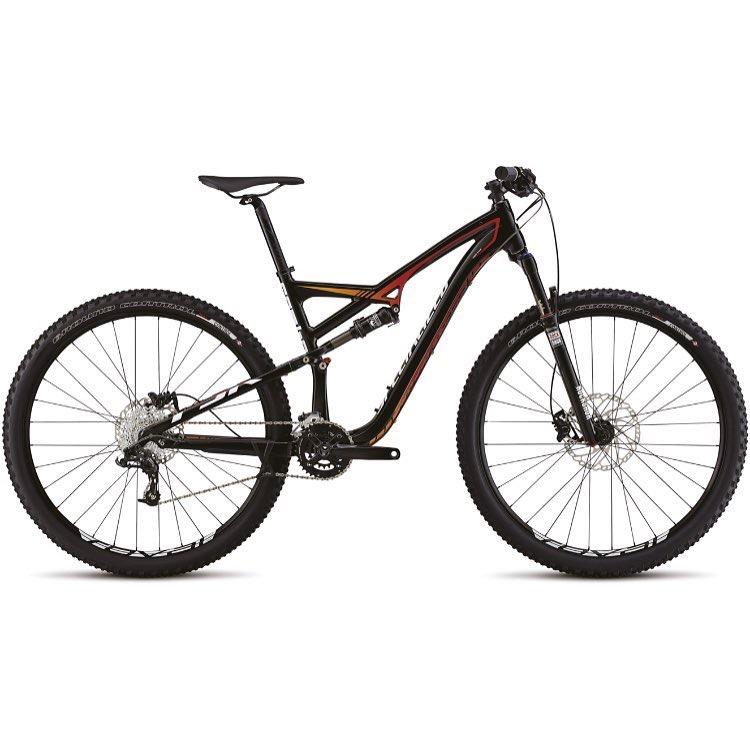 Specialized Camber Comp 29: A high-performance mountain bike featuring a black frame with red and orange accents, front and rear suspension, and large knobby tires designed for off-road terrain. The bike is shown in profile, highlighting its sleek design and disc brakes.