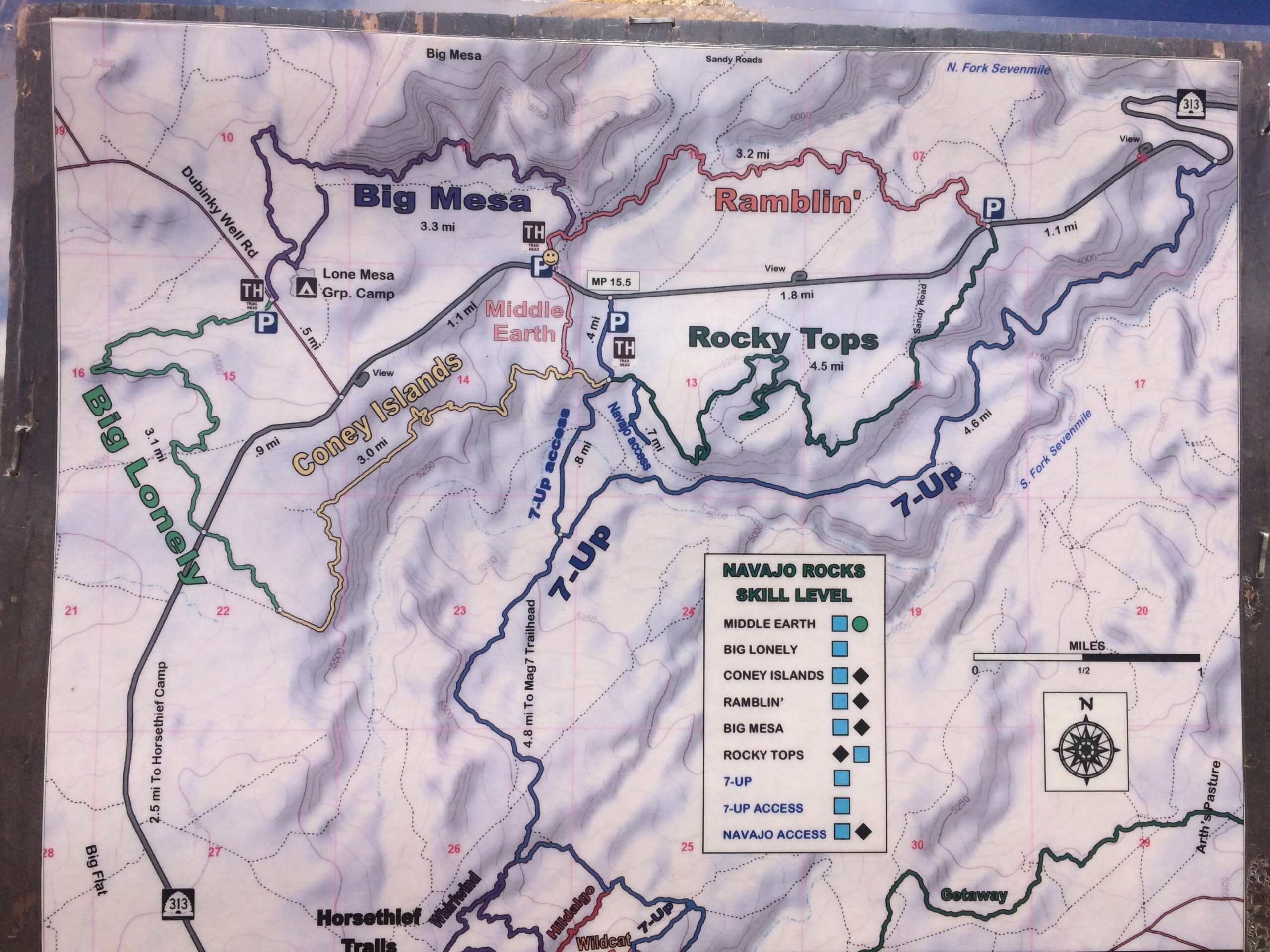 Map of Navajo Rocks area showing various trails, including Big Mesa, Middle Earth, and Rocky Tops, along with their respective distances and skill levels. Key features include parking areas, group camp locations, and trail access points. The map includes a compass rose and a scale indicating miles. Navajo Rocks mountain bike trail.