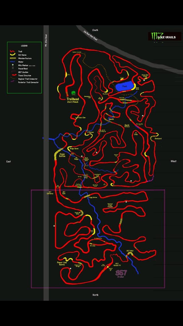 A detailed trail map showing various bike trails in a wooded area. The map features red lines representing the trails, with blue lines indicating water features and yellow lines marking dirt burn areas and other landmarks. Key points such as the trailhead, mile markers, and specific trails are labeled. The orientation of the map is indicated with North at the top and other cardinal directions along the sides. Mt. Zion Bike Trails mountain bike trail.