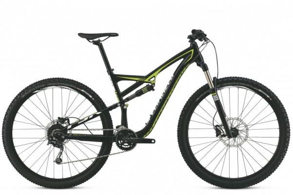 Specialized Camber 29: Mountain bike with a black frame and green accents, featuring thick tires, a front suspension fork, and disc brakes. The bike is shown from the side, highlighting its sporty design and mountain biking capabilities.