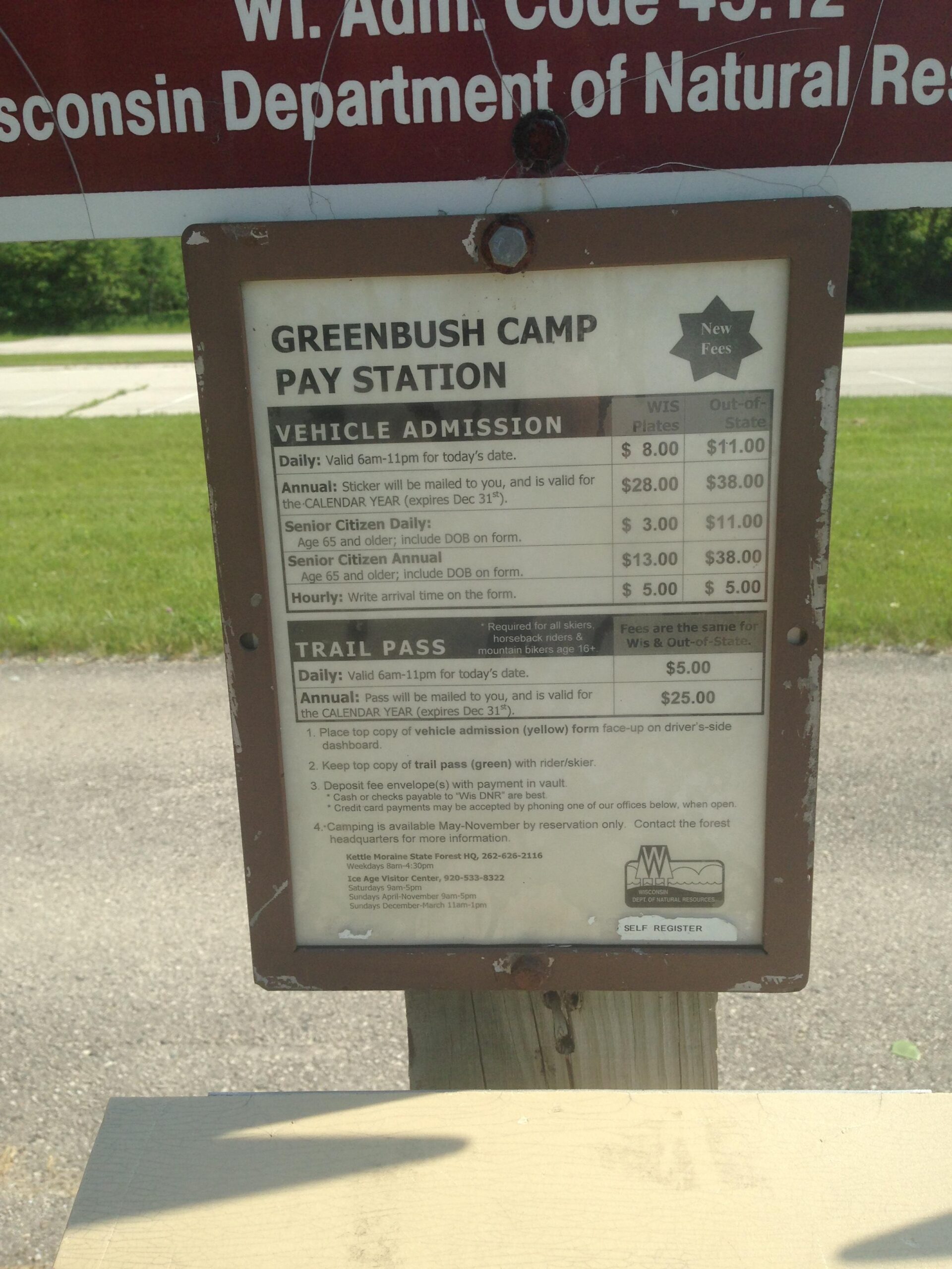 Sign at Greenbush Camp Pay Station detailing vehicle admission and trail pass fees. It includes daily, annual, and senior citizen rates for Wisconsin residents and out-of-state visitors, along with instructions for payment and registration. Greenbush mountain bike trail.