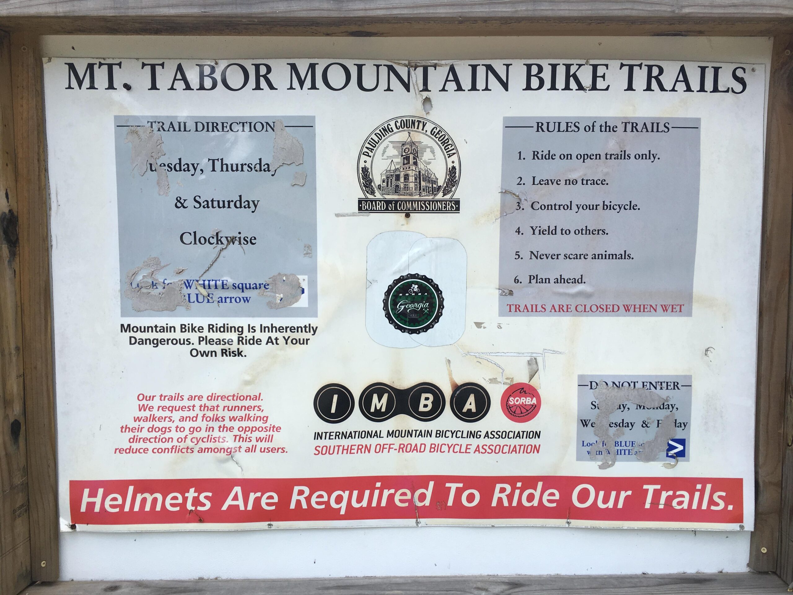 Signage for Mt. Tabor Mountain Bike Trails, detailing trail directions for specific days of the week, rules for trail use, and a warning about the inherent dangers of mountain biking. It includes instructions for respecting trail etiquette and requirements for wearing helmets. Mt Tabor Park mountain bike trail.