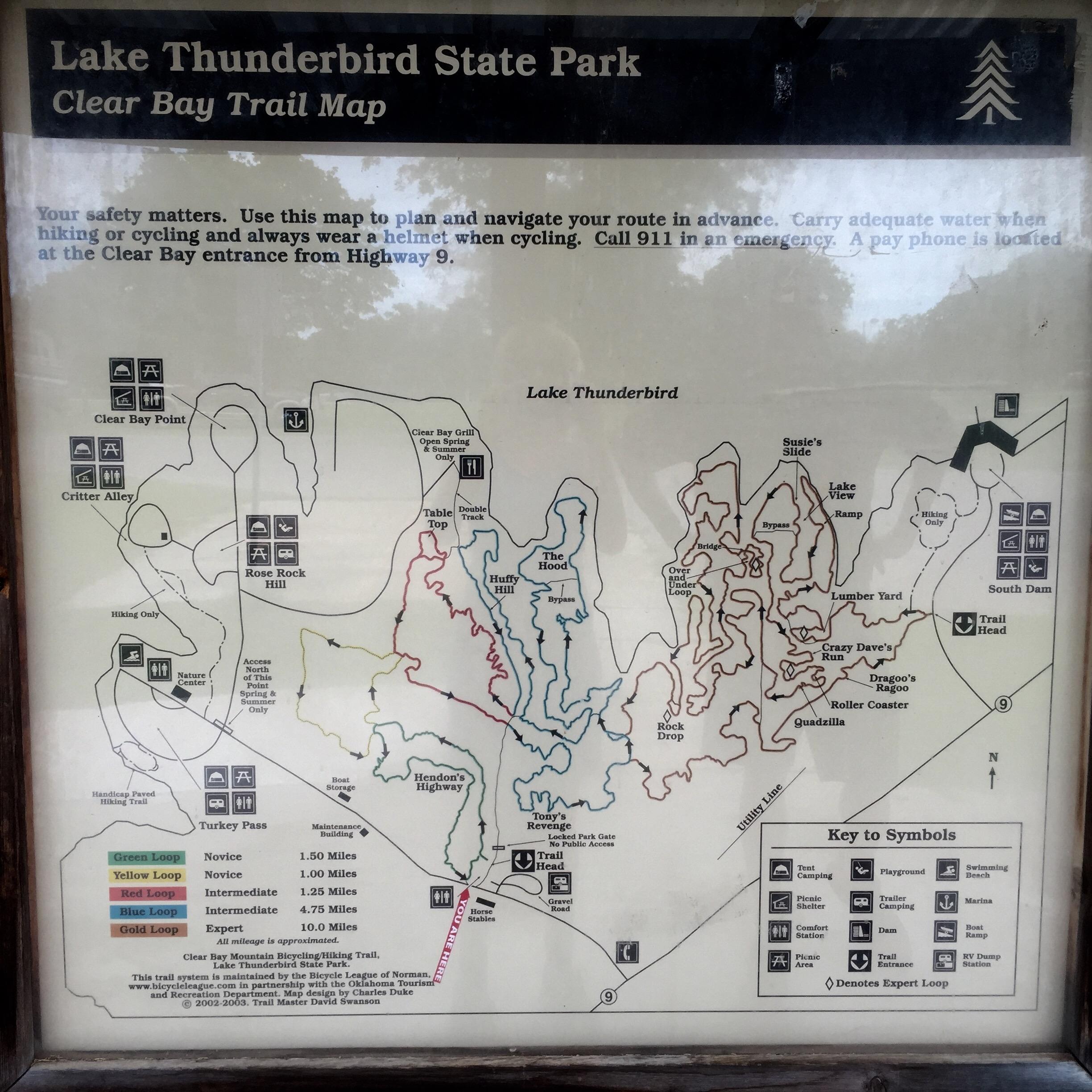 Map of Lake Thunderbird State Park's Clear Bay Trail, detailing various hiking and cycling routes, safety information, and key symbols for points of interest. It includes designated loops for different skill levels and highlights features like trailheads, rest areas, and natural attractions. Thunderbird Lake Clear Bay mountain bike trail.