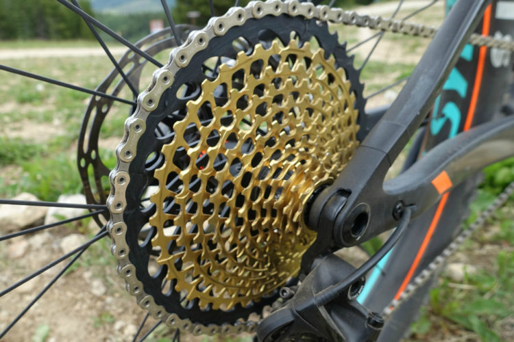 Close-up view of the SRAM Eagle 1x12 drivetrain, featuring a gold-colored cassette and corresponding chain on a mountain bike. The background shows a natural outdoor setting. Text at the top indicates it is the "Readers' Choice for Most Innovative Product of 2016."