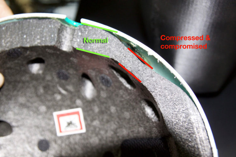 Interior view of a helmet showing two areas labeled with different statuses. The green label indicates a "Normal" area, while the red label indicates a "Compressed &amp; compromised" area, highlighting the differences in the helmet's structural integrity. The black padding and additional details of the helmet interior are visible in the image.