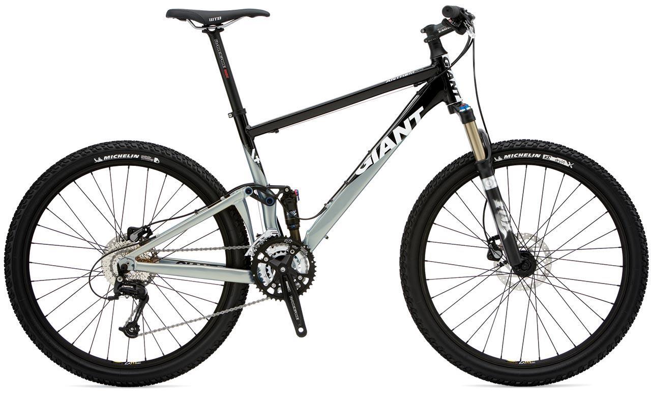Giant Anthem 2: A side view of a mountain bike with a black and silver frame, featuring wide tires and disc brakes. The bike has a curved top tube, front suspension fork, and a raised seat. The wheels are adorned with Michelin branding.