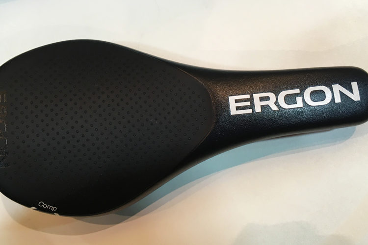 A close-up view of a black bicycle saddle featuring a smooth design, with the brand name "ERGON" prominently displayed in white lettering. The saddle has a textured surface for added grip and comfort.