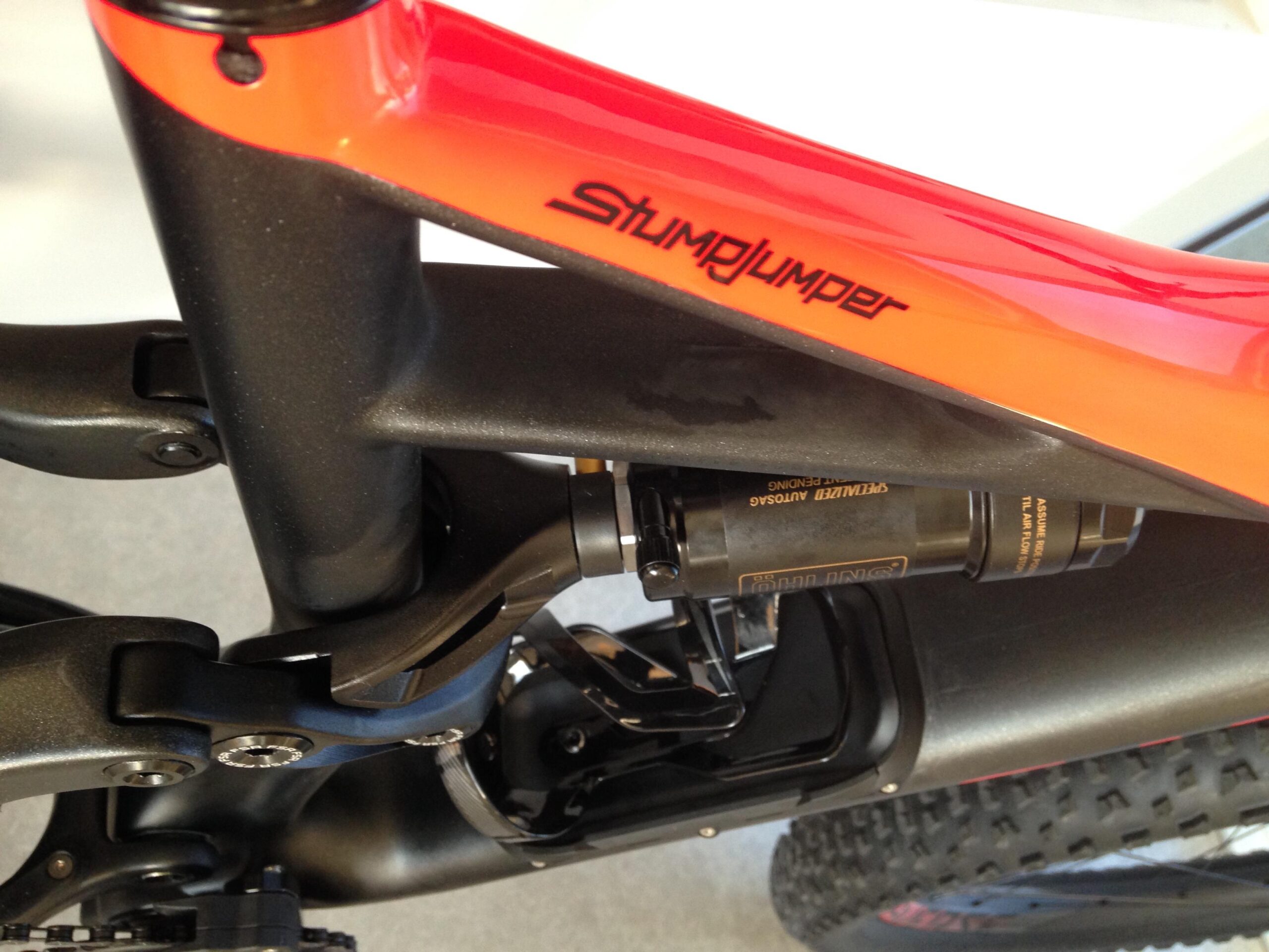 Specialized Stumpjumper FSR 6Fattie: Close-up image of a mountain bike frame featuring a vibrant orange and black color scheme. The shot highlights the rear suspension mechanism and the "Stumpjumper" branding on the top tube, showcasing the bike's design and engineering details.