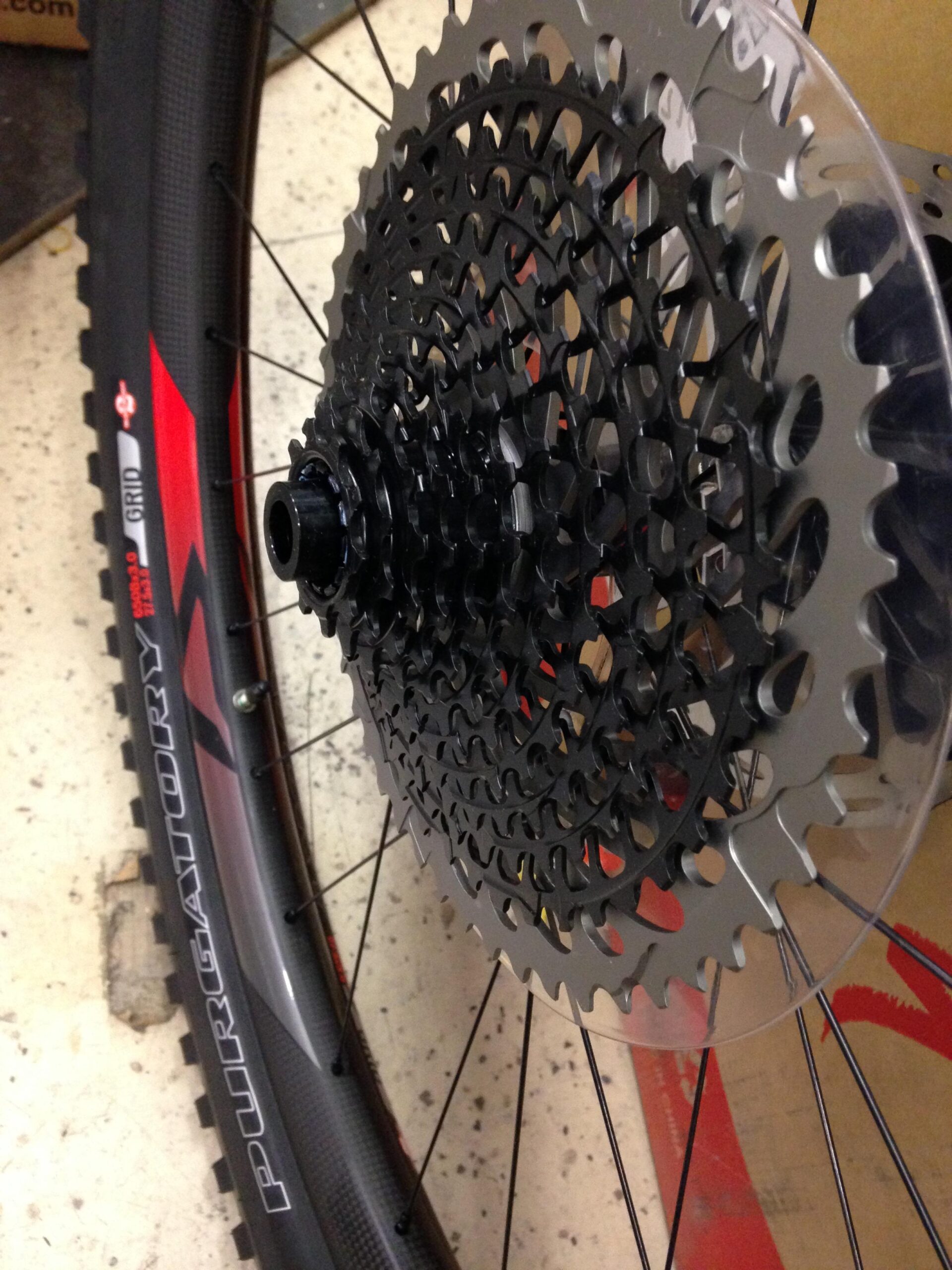 Close-up of a bicycle cassette mounted on a wheel, showing the intricate gear design and a partially visible tire labeled "PURGATORY."