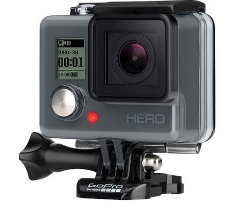 GoPro Hero: A GoPro HERO action camera, showcasing its compact design, front display, and lens. The camera is mounted on a black adjustable clip, designed for versatile mounting options, with control buttons and a small LCD screen visible on the front.