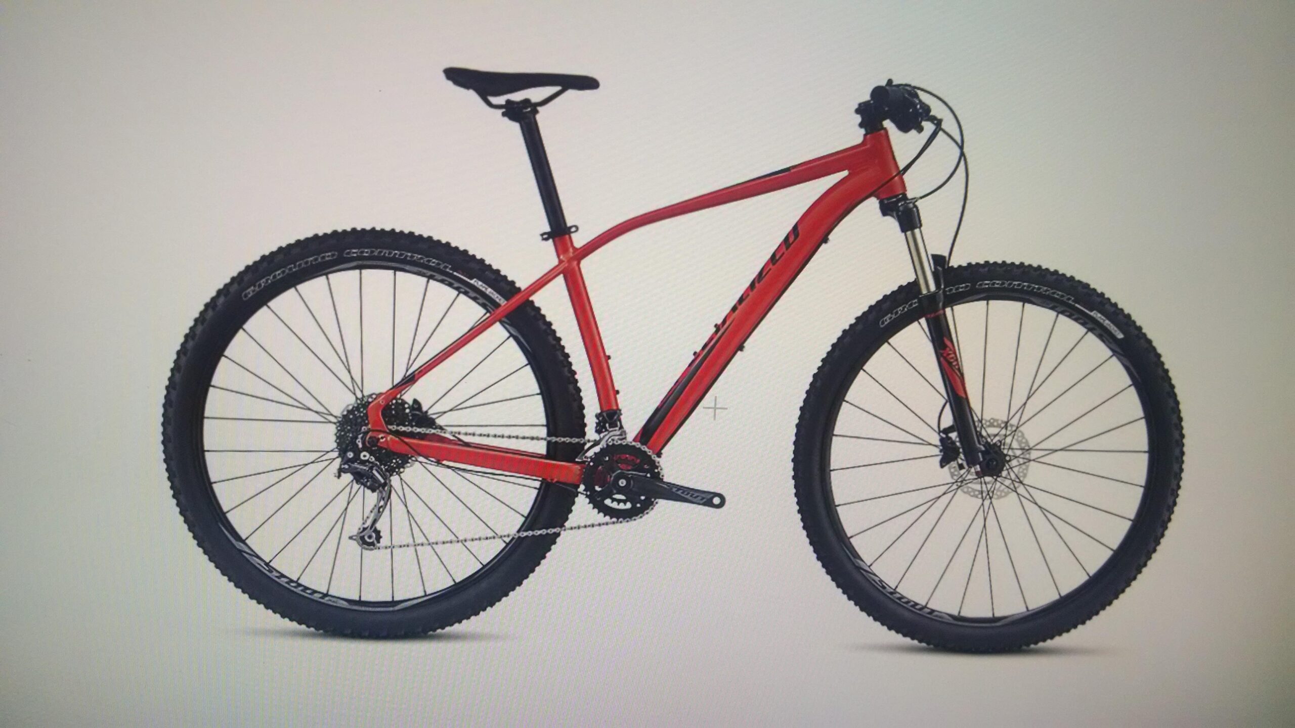 Specialized Rockhopper Comp 29: A red mountain bike with wide tires and a lightweight frame, positioned on a plain background. The bike features front suspension, a sleek design, and visible gears and brakes.