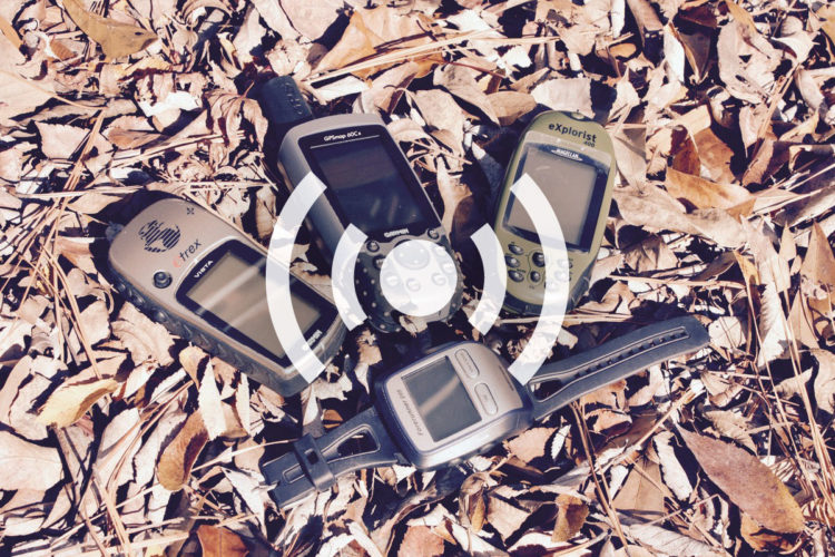 A collection of GPS devices arranged in a circular formation on a bed of dried leaves. The devices include models from Garmin, eTrex, and Magellan. A circular signal icon is overlaid in the center of the image.