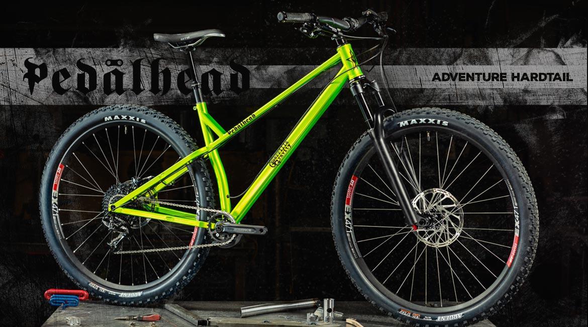 Guerrilla Gravity Pedalhead: A bright green adventure hardtail mountain bike positioned on a workbench, showcasing its sturdy frame and Maxxis tires. The background features a dark, textured pattern with the words "Pedalhead" and "ADVENTURE HARDTAIL" prominently displayed.