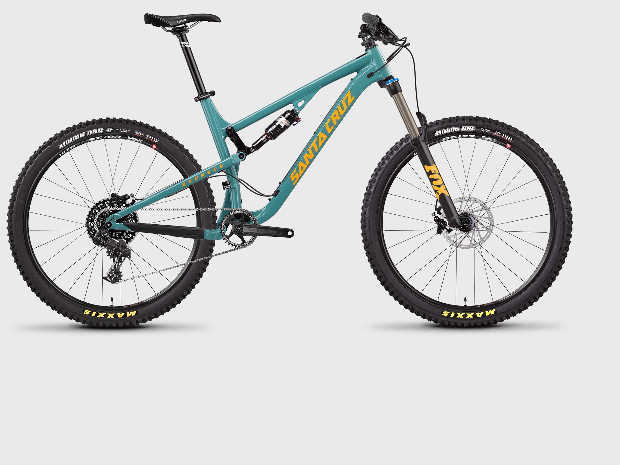 Santa Cruz Bronson: A turquoise mountain bike with yellow accents and large tires, featuring a dual suspension system, prominent gear components, and a sleek design, displayed on a plain background.